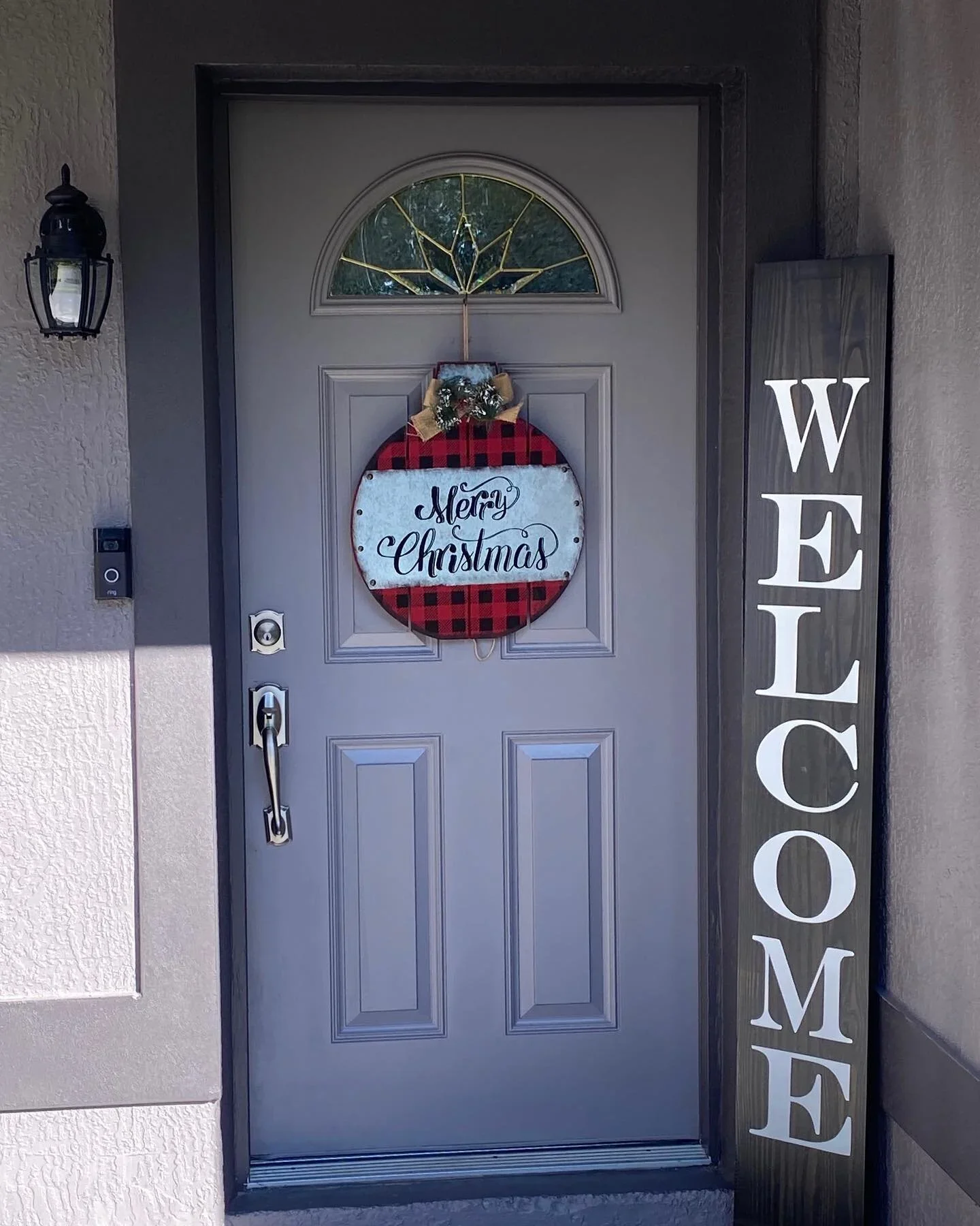 Front door decorated for Christmas with a wreath, a sign that says "Merry Christmas," and a vertical wooden sign that says "WELCOME" on the side.