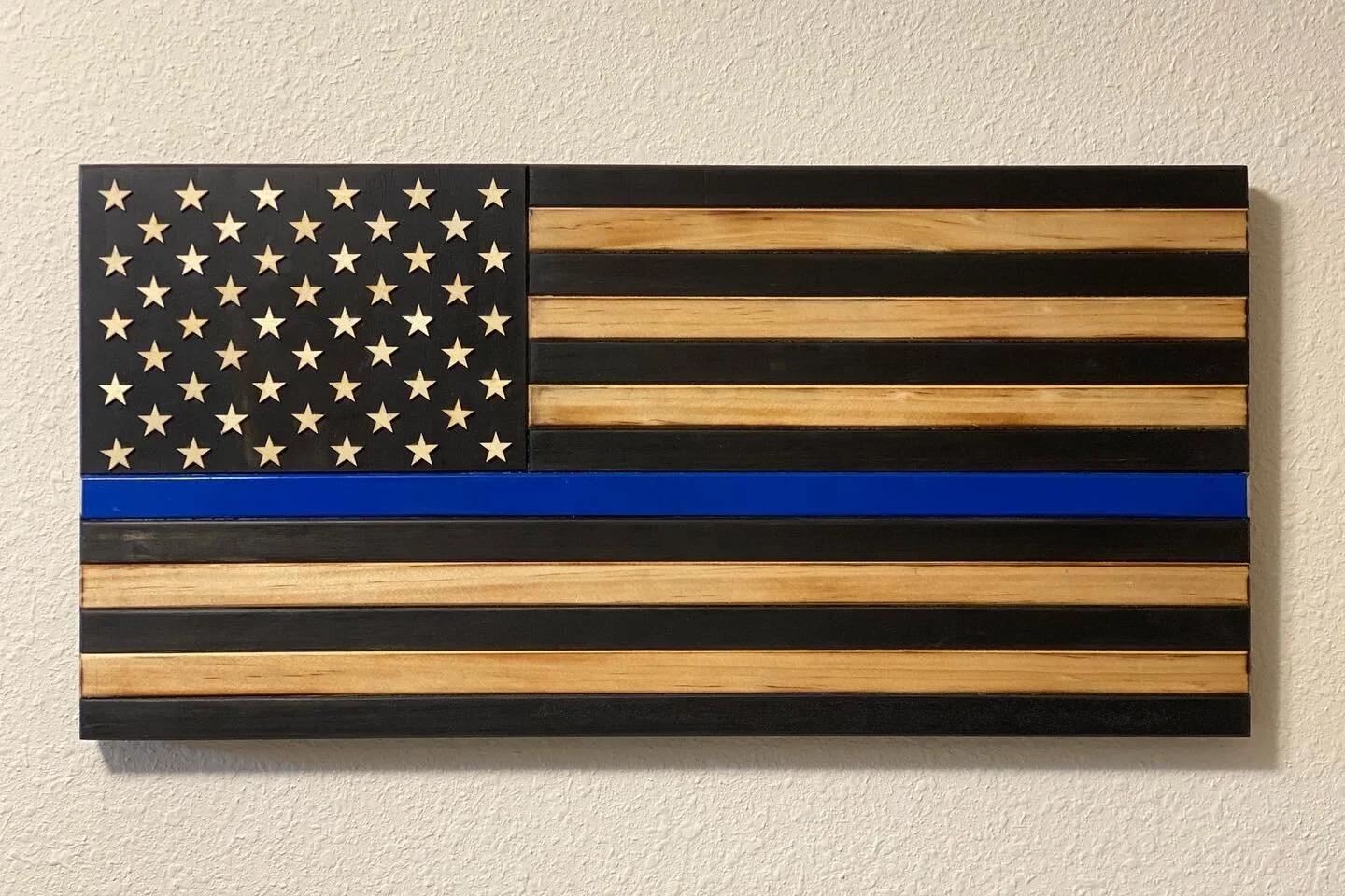 Wooden American flag wall art with a black, natural wood, and blue line design.