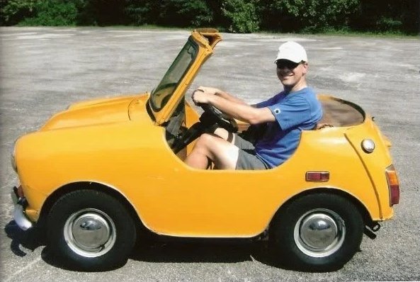 Barclay R. Brown smiling in a small yellow car