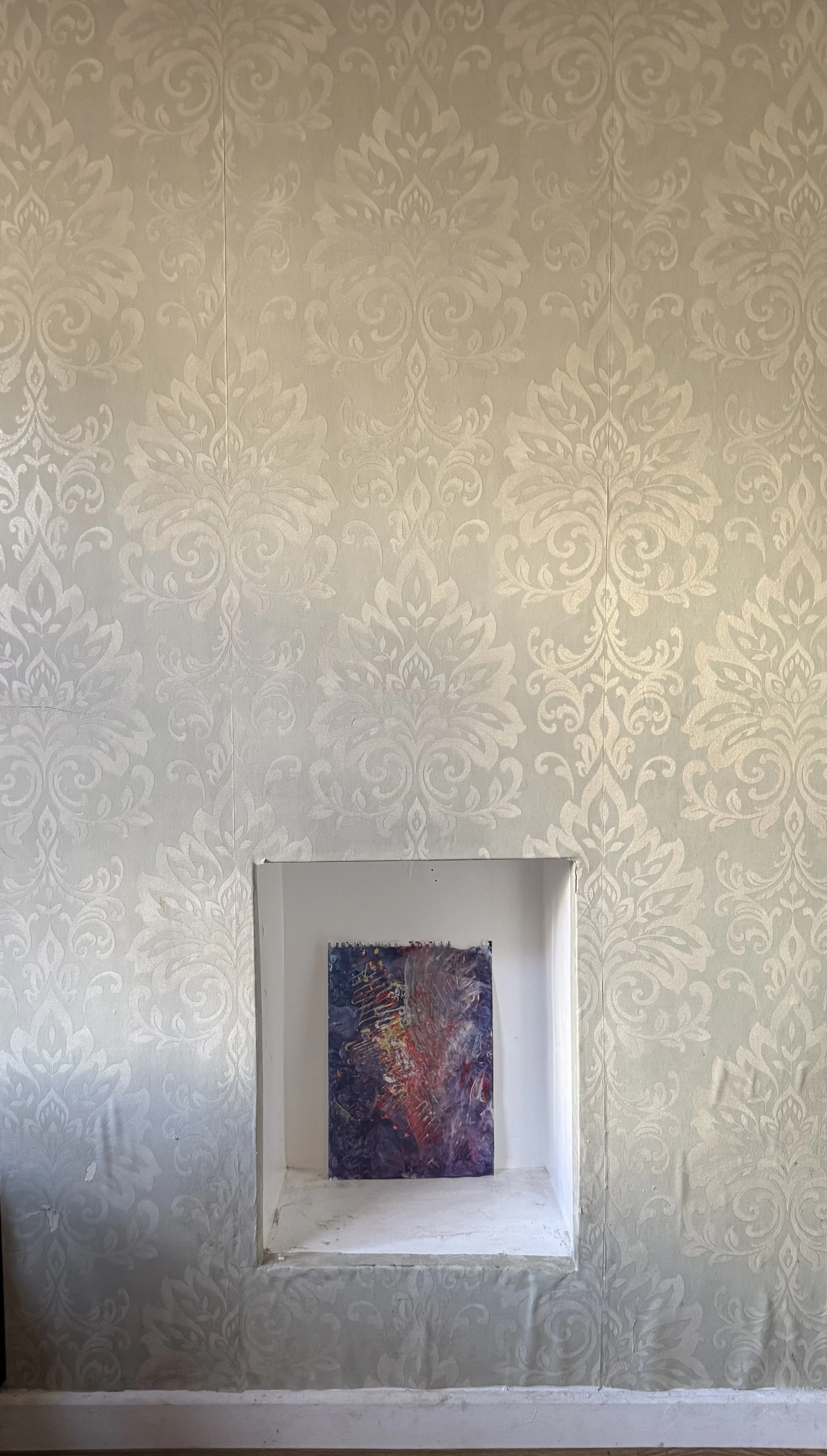 Wall with decorative wallpaper featuring a large damask pattern, centered niche with an abstract colorful painting made by Evie Sofia Forrest Norton (EVSN) at age 1.