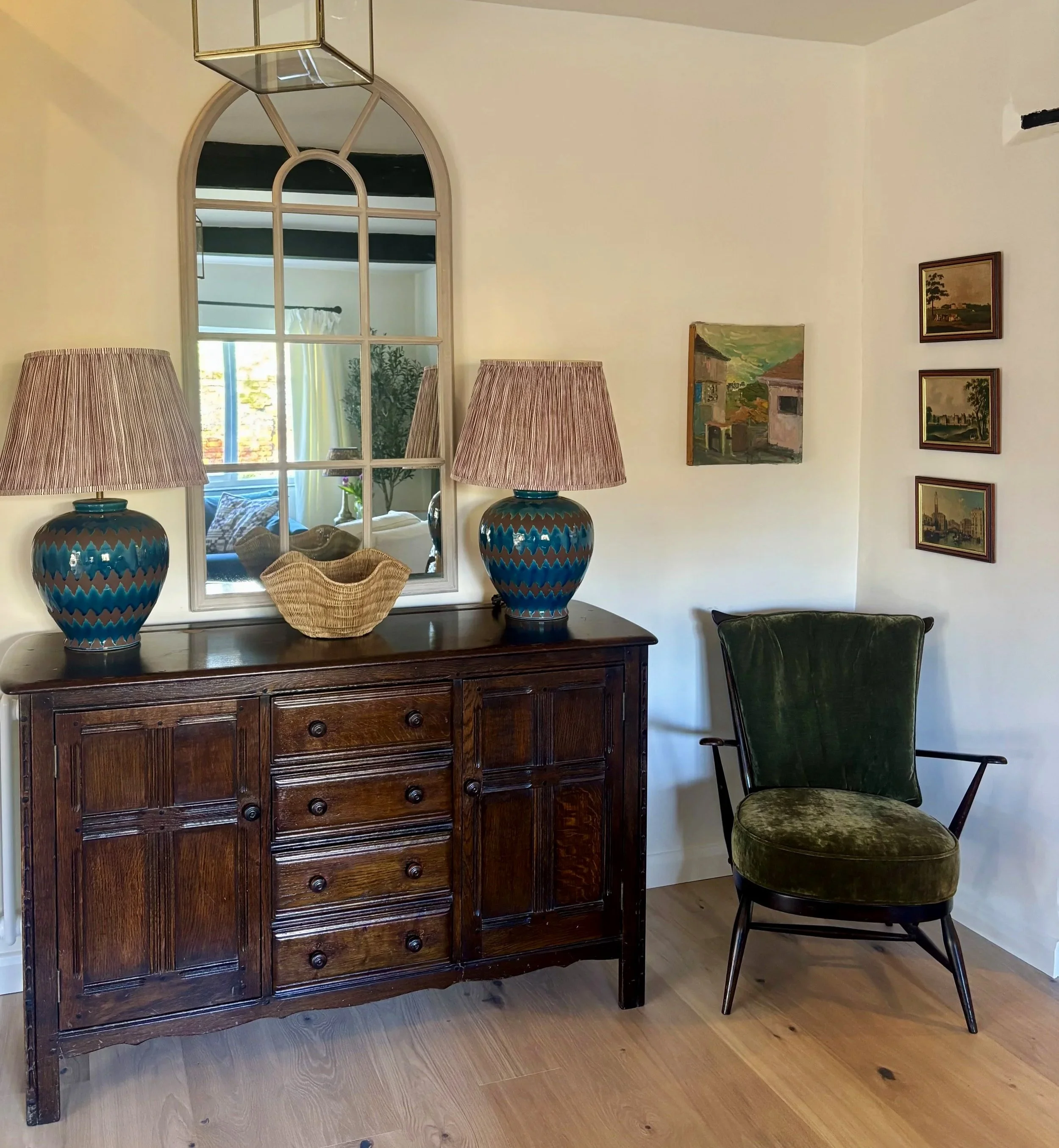 vintage wooden sideboard with large blue lamps and mirror above it.  vintage wooden armchair with green cushions