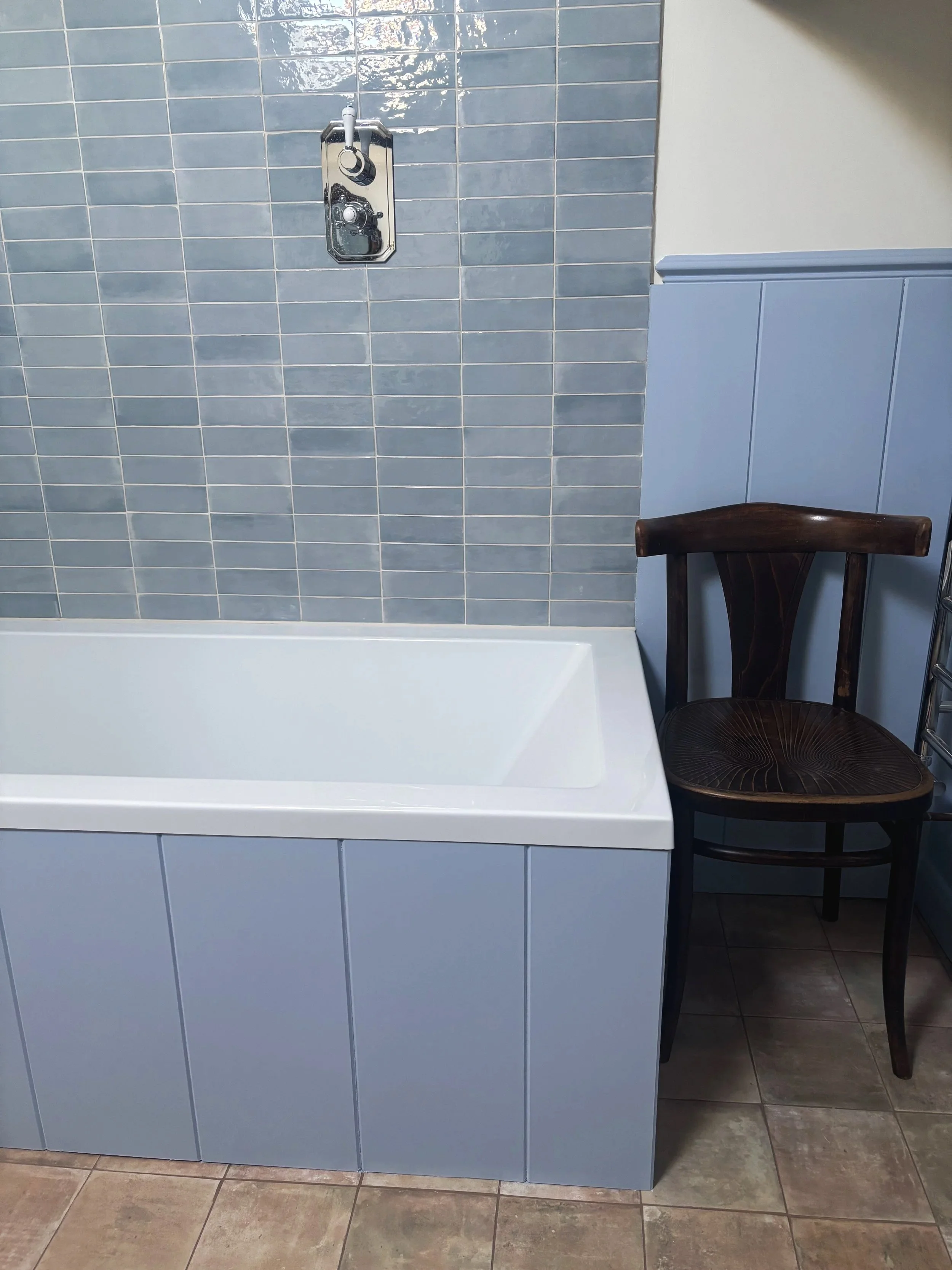 blue bathroom with terracotta tiles and a vintage chair