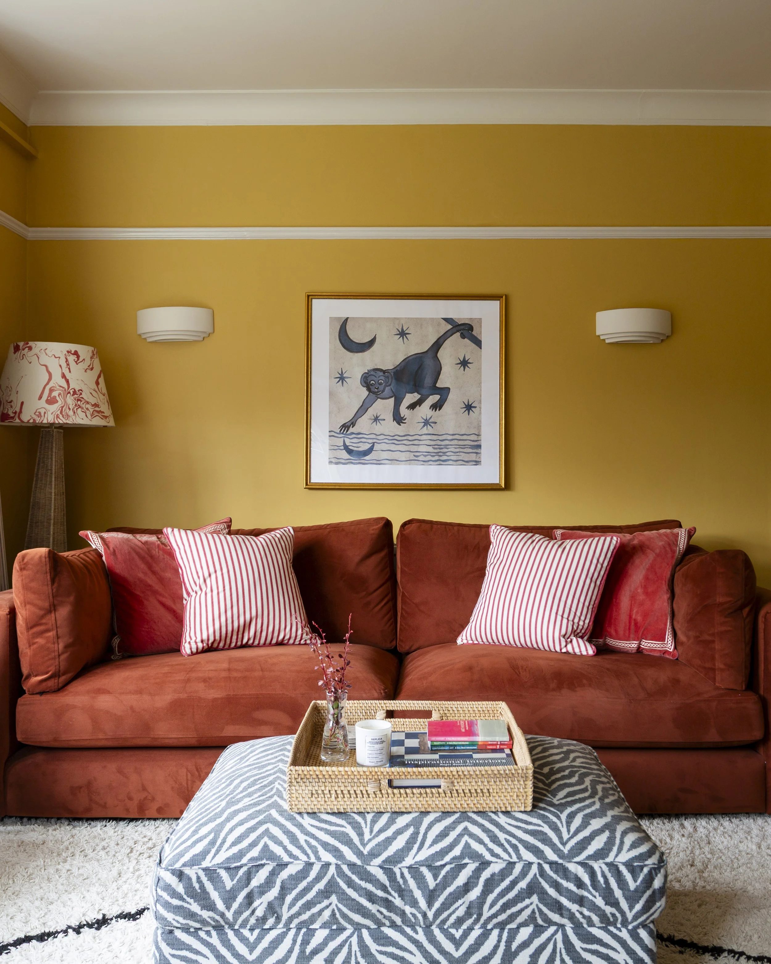 living room with yellow walls, a rust sofa and zebra ottoman