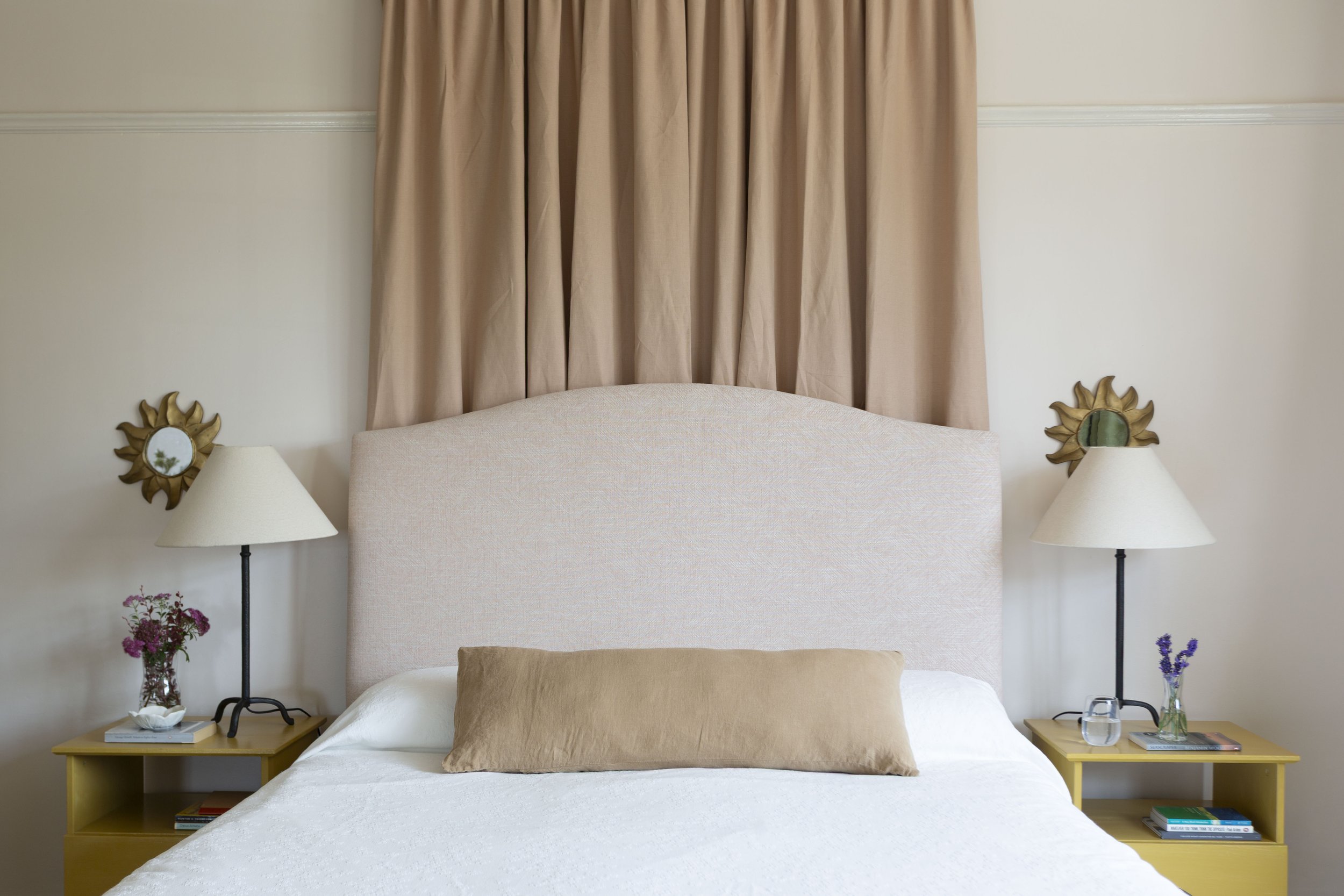 bedroom showing bed with pink curtain canopy and yellow bedside table with lamp
