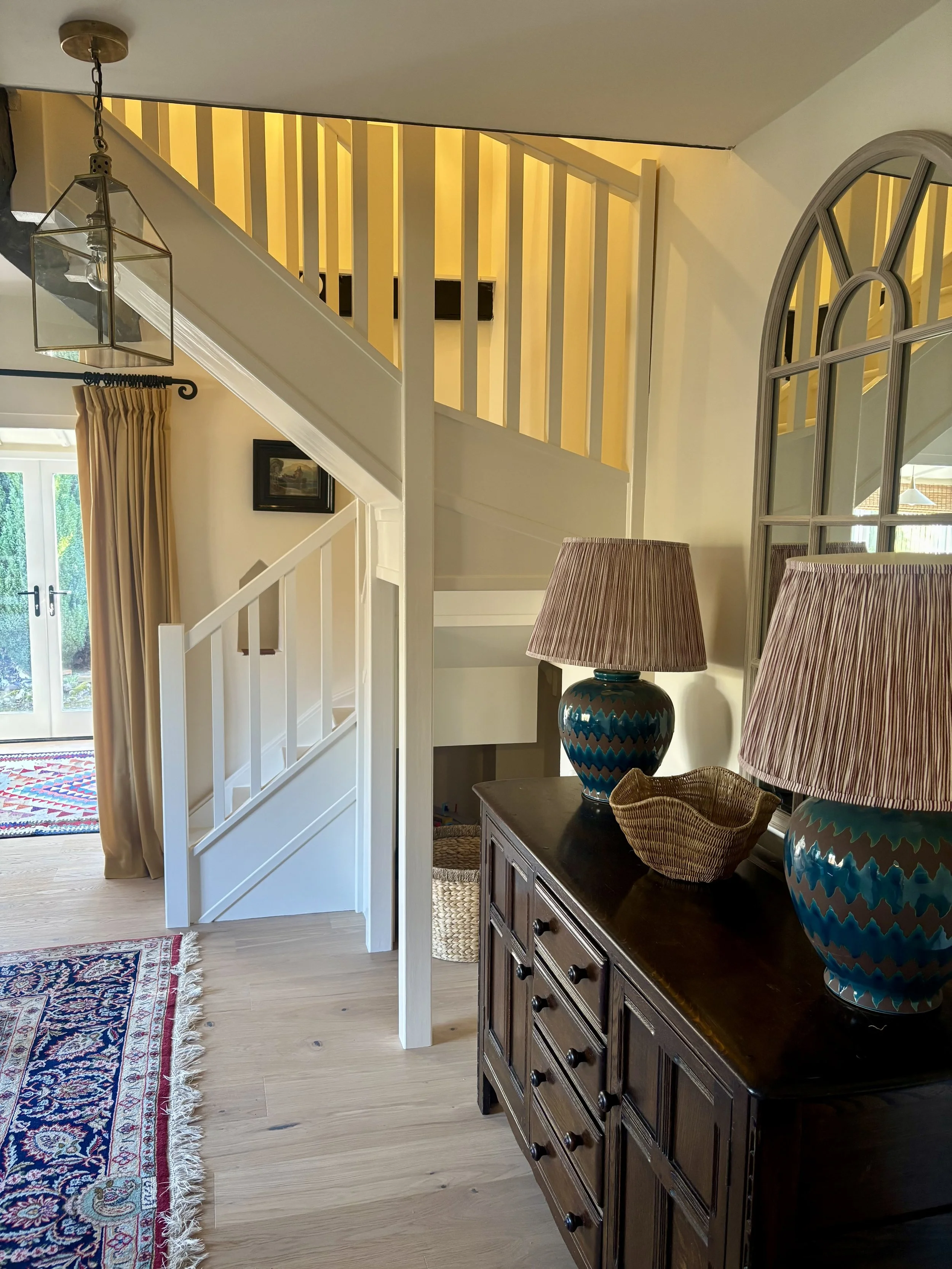 vintage wooden sideboard with large blue lamps and mirror above it next to set of stairs