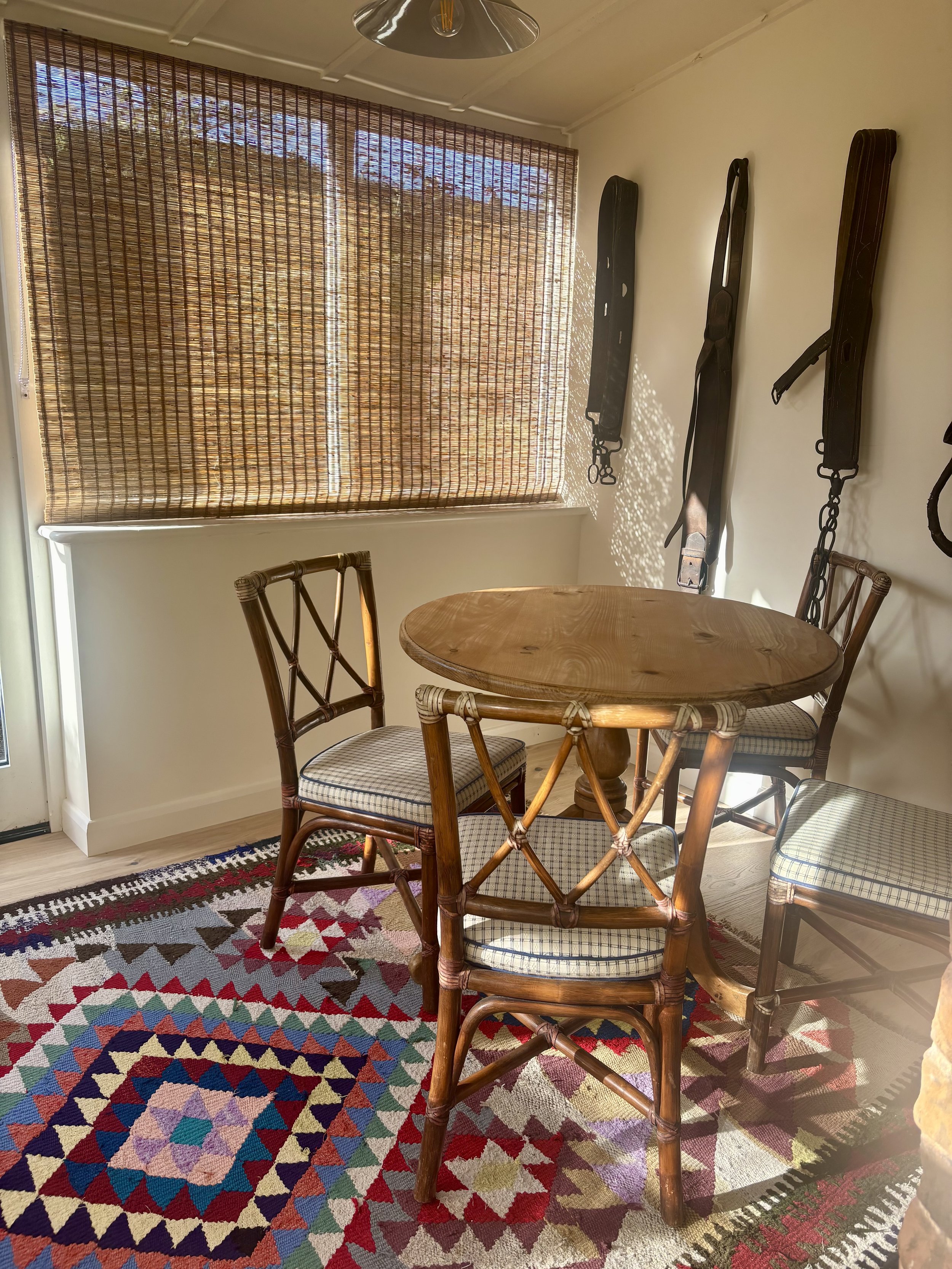 sun room with vintage dining table and chairs, wicker blinds and a colourful patterned rug