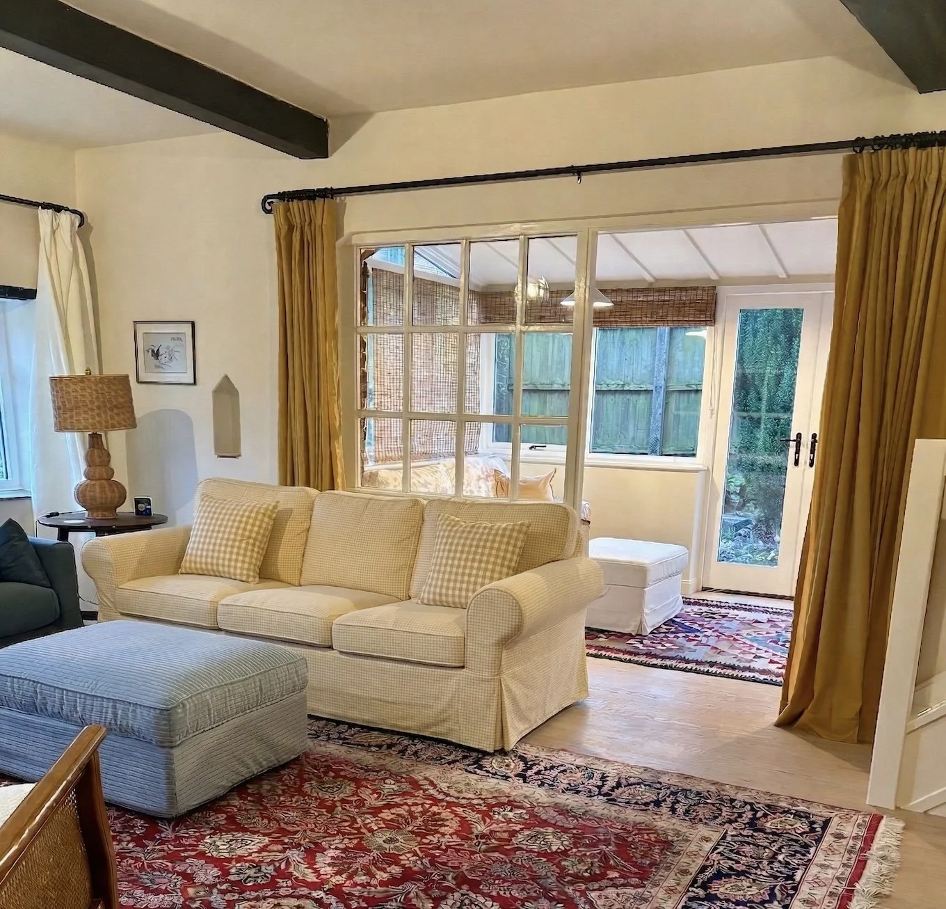 colourful living room with blue ottoman. yellow sofa and curtains and Persian rug