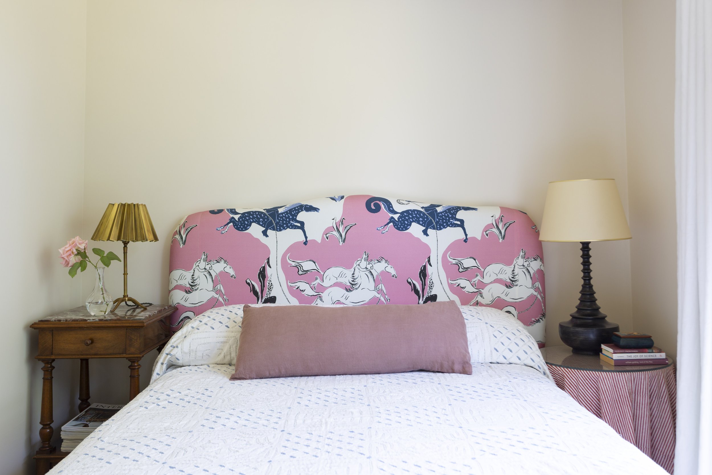guest bedroom with a Pierre Frey headboard in pink with navy horses.  Wooden and tablecloth bedside tables with lamps
