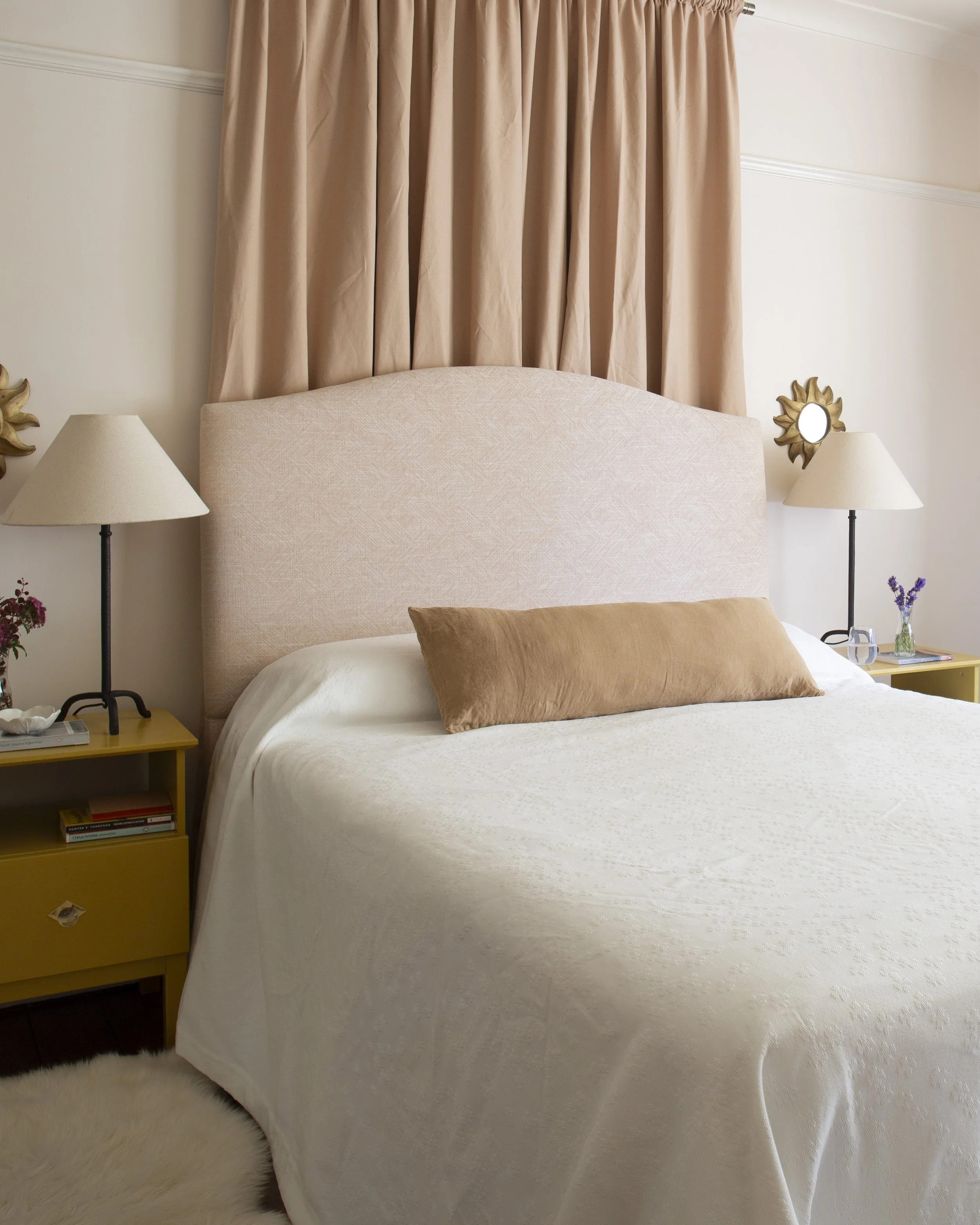 bedroom with pink bed and canopy. yellow bedside tables and simple lamp