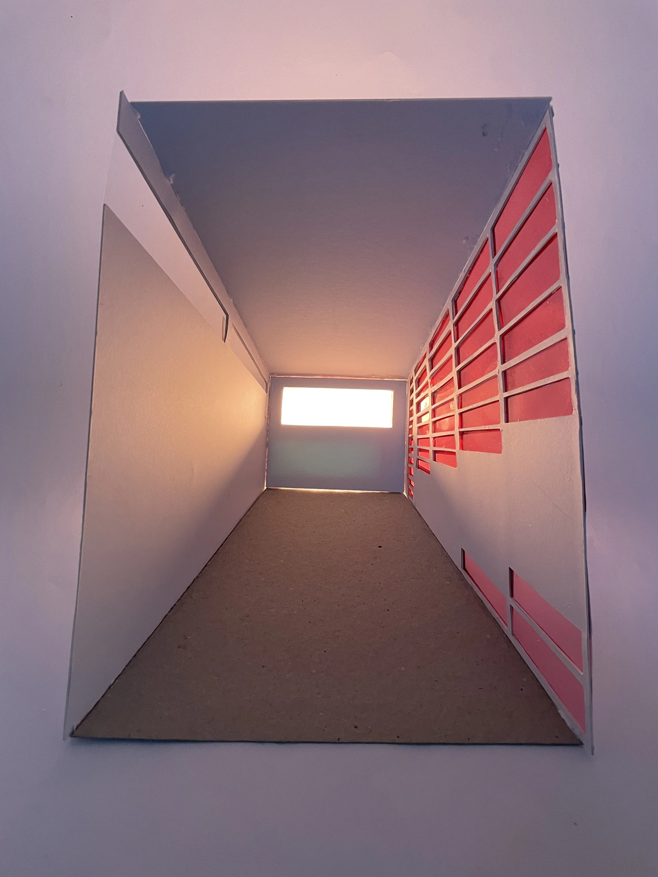 A cardboard cabinet with holes on the right side and a small rectangular window on the far wall, showing a white background.