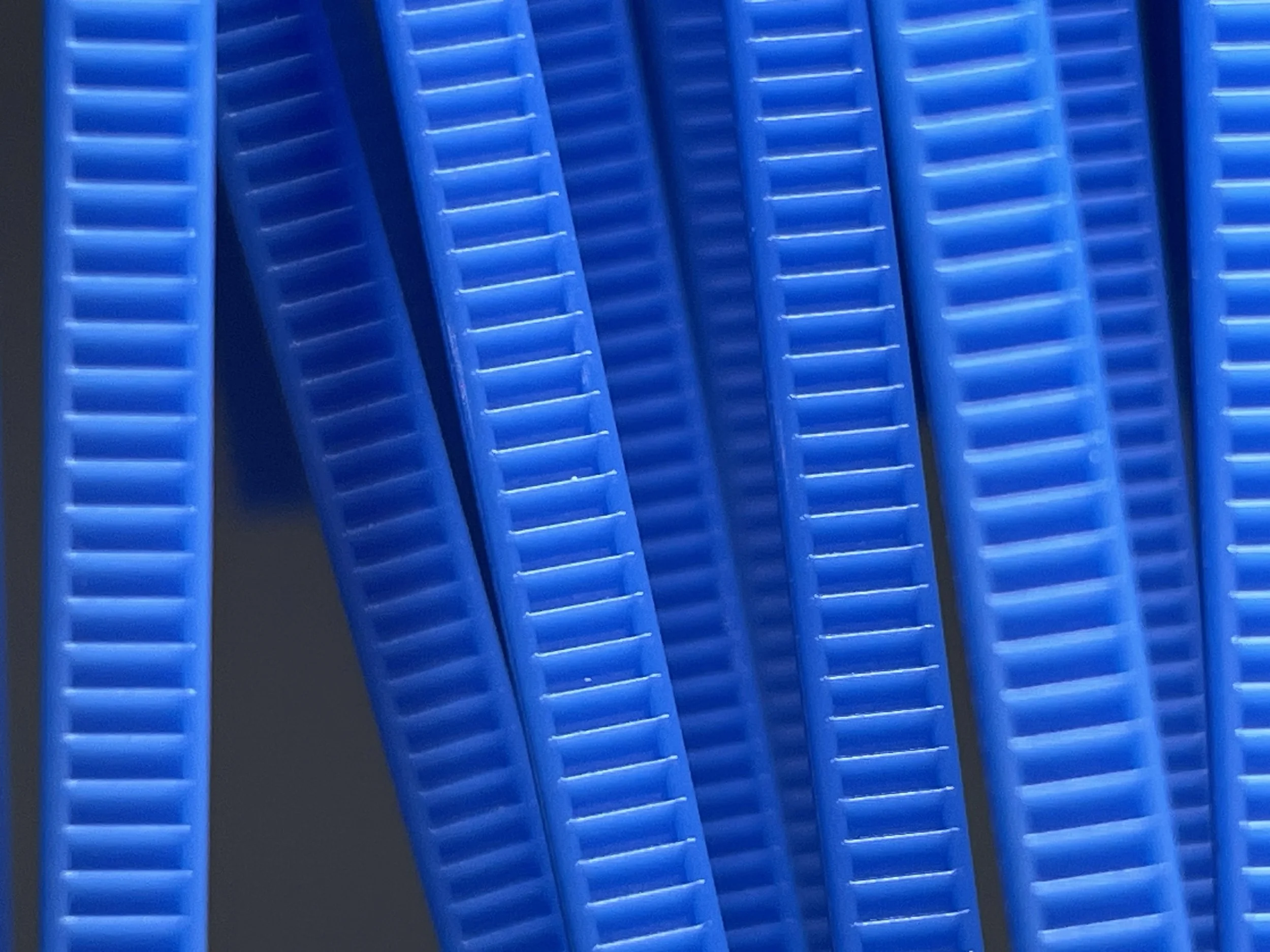 Close-up of numerous blue plastic zip ties arranged vertically.