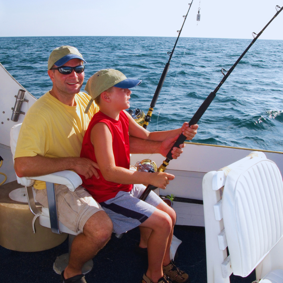 A man and a boy fishing on a boat in the ocean.