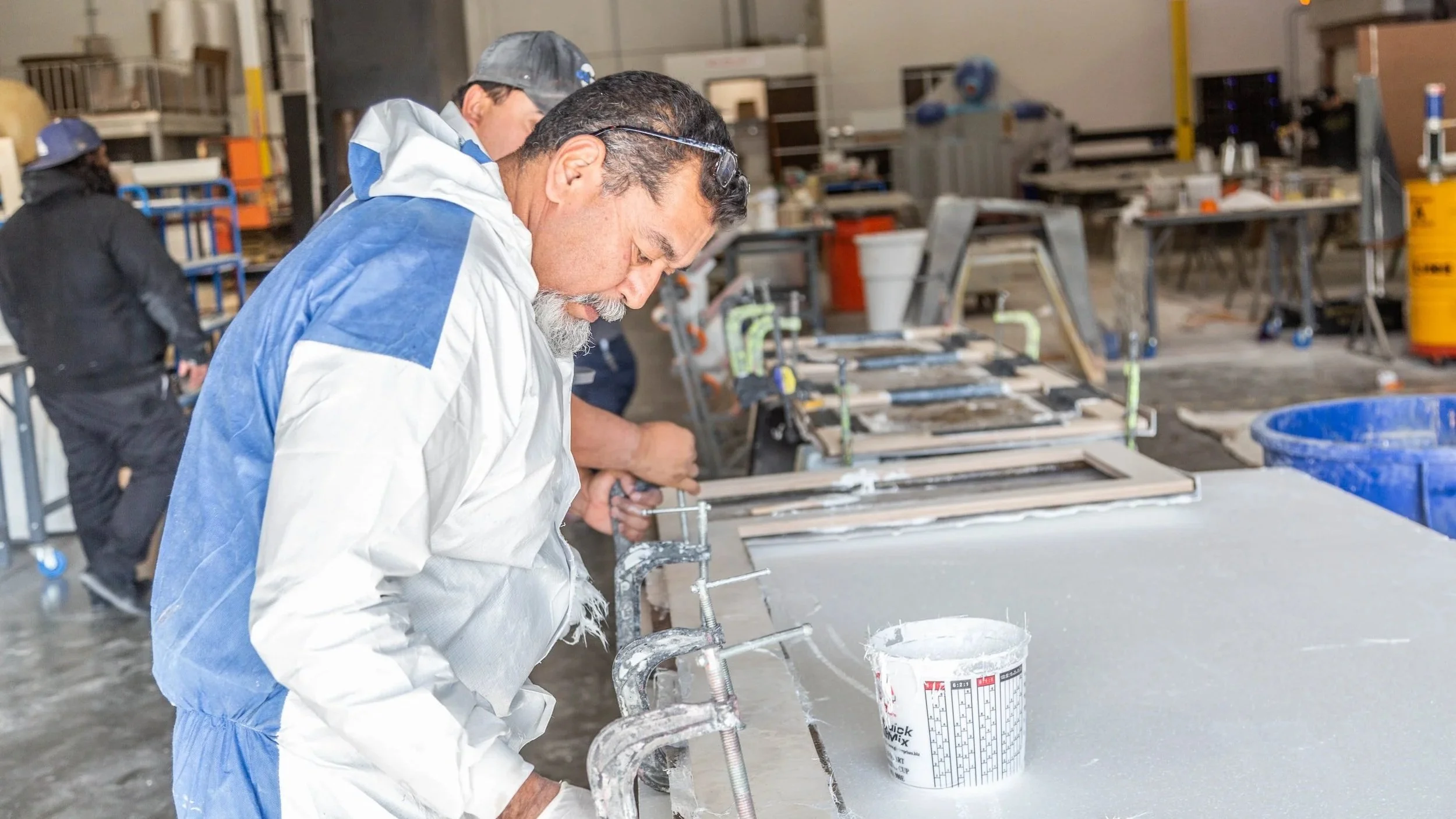 Person wearing protective gear working on a project in a workshop filled with tools and equipment