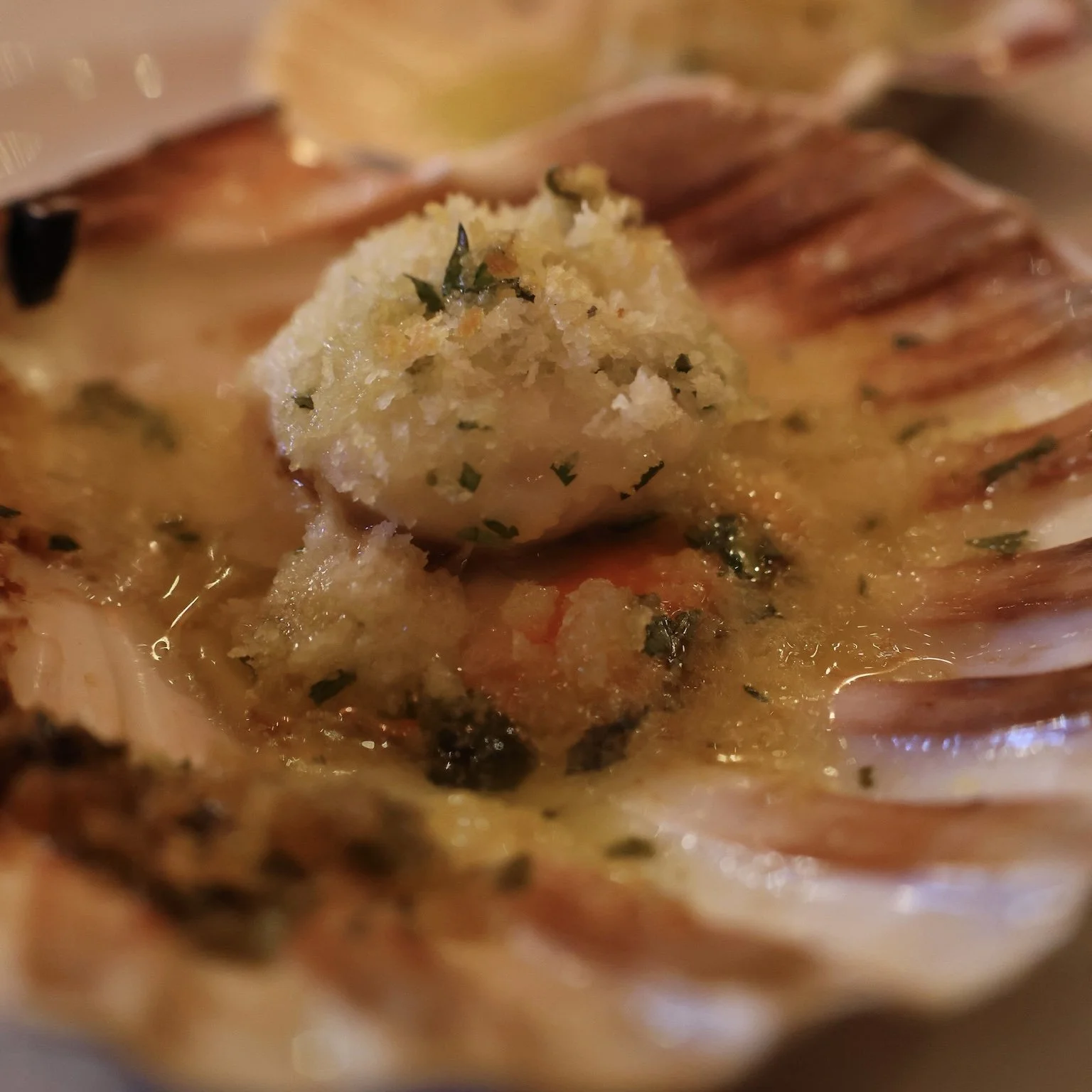 Close-up of a garlic butter shrimp in a shell with herbs.