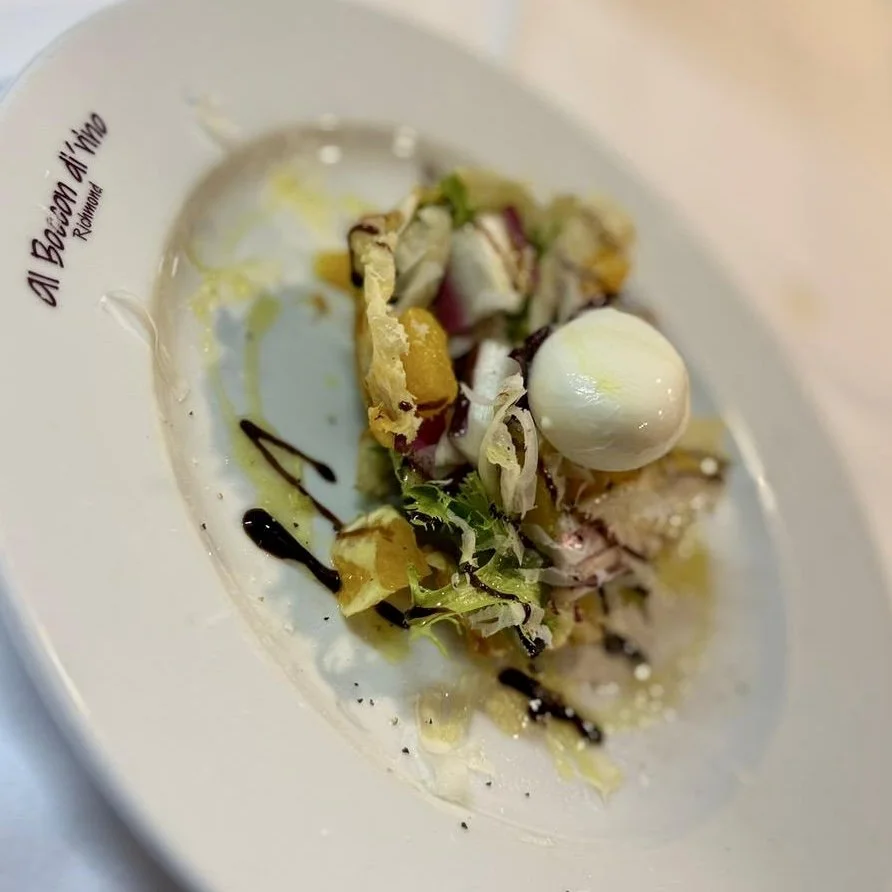A plate with a small portion of salad or appetizer, including a white ball, greens, chopped vegetables, and drizzled balsamic vinegar or sauce, on a white dish from Al Bawadi in Riyadh.