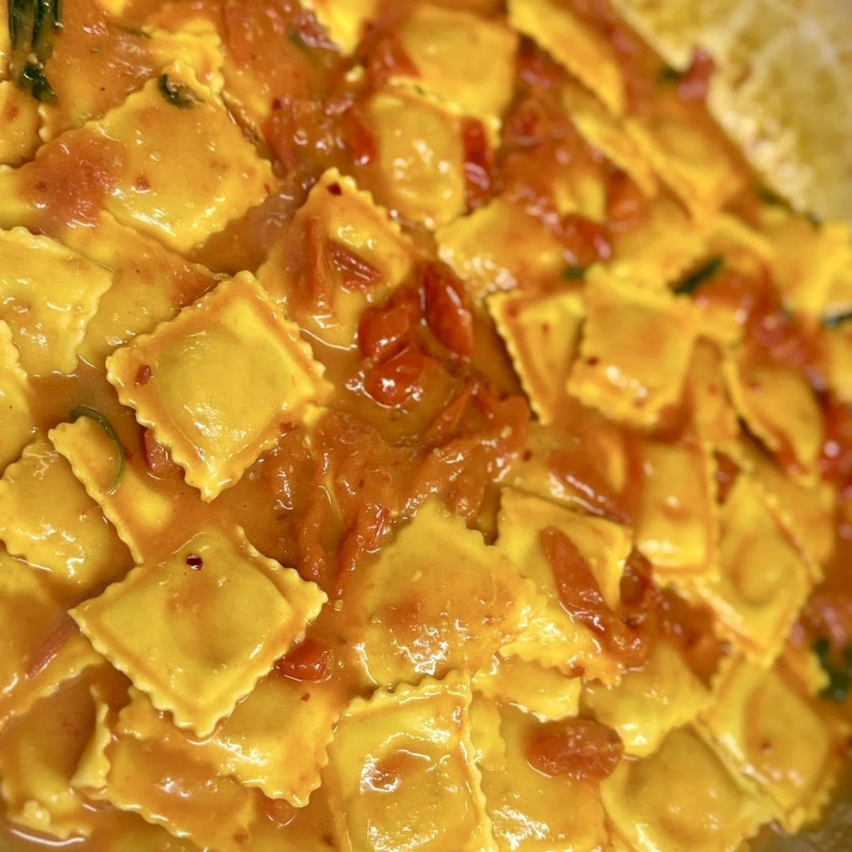 Close-up of cooked ravioli pasta with tomato sauce and herbs.