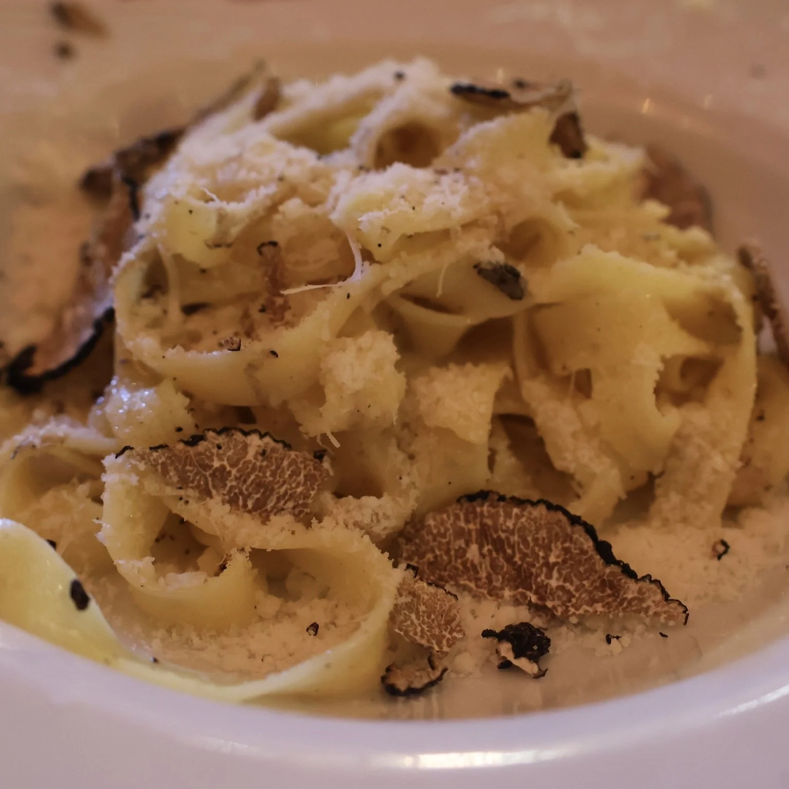 Close-up of truffle pasta topped with shaved black truffles.