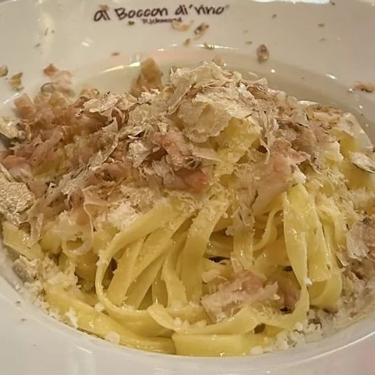 A plate of Italian pasta with tuna, grated cheese, and a creamy sauce.