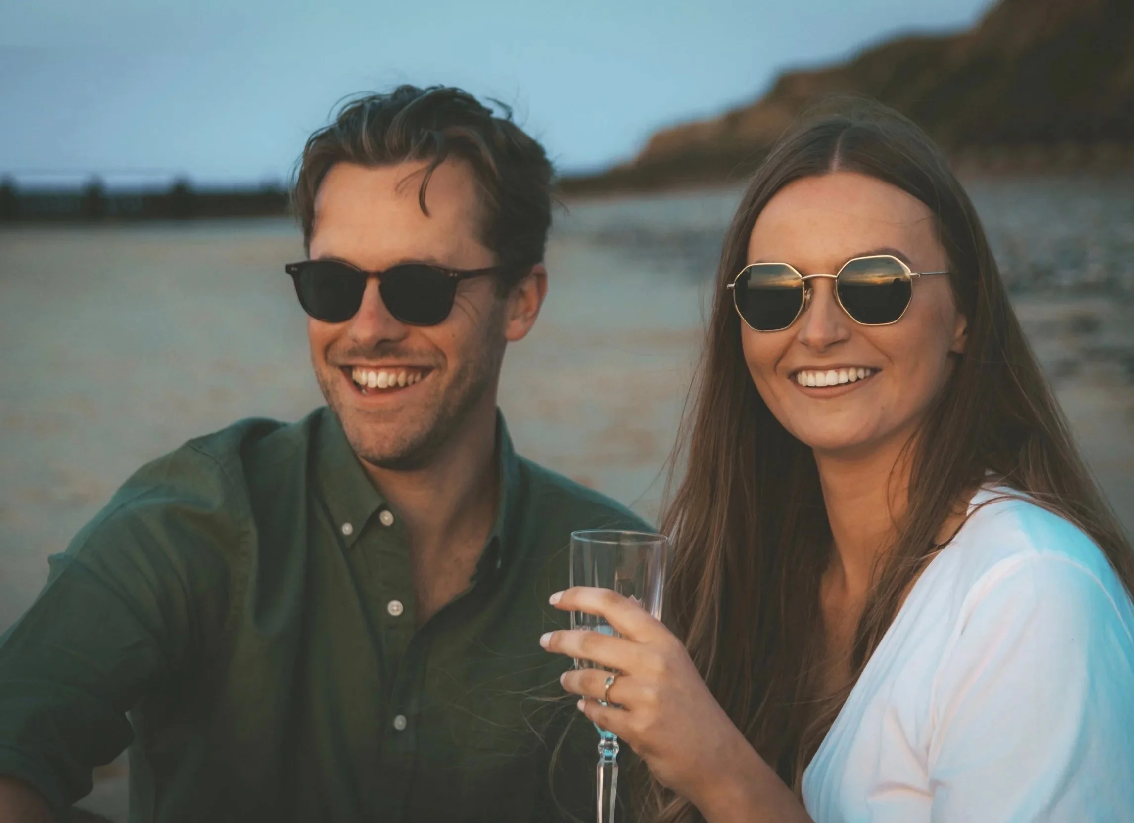 Couple smiling together on a Norfolk beach at sunset during an engagement photography session.