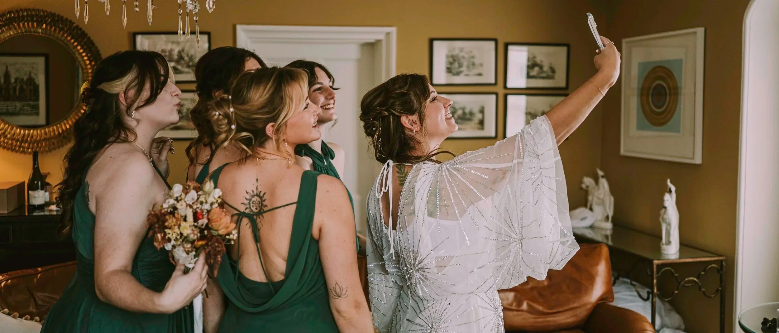 Bride and bridesmaids taking a selfie together during wedding preparations.