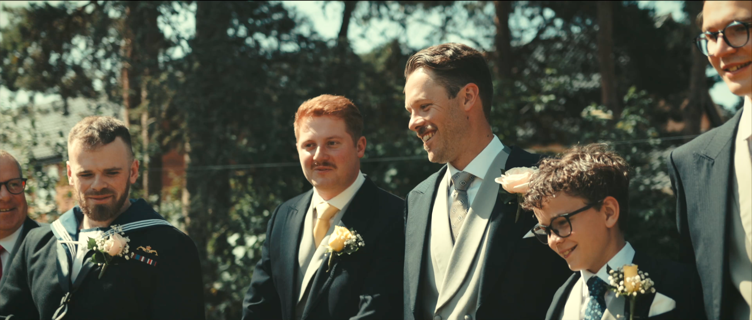 Groomsmen smiling together during an outdoor wedding ceremony in Norfolk.