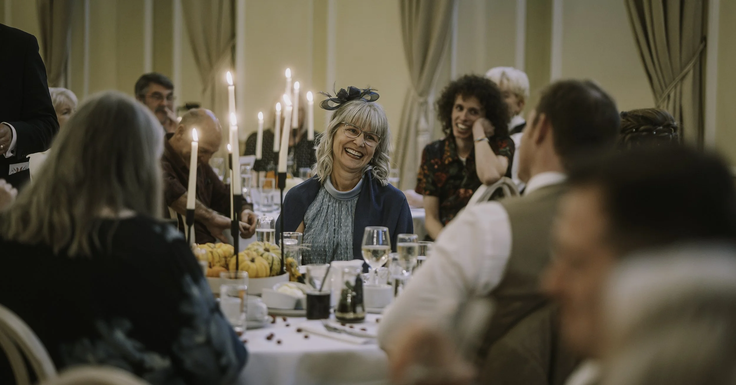 Guests laughing during wedding speeches at the reception.