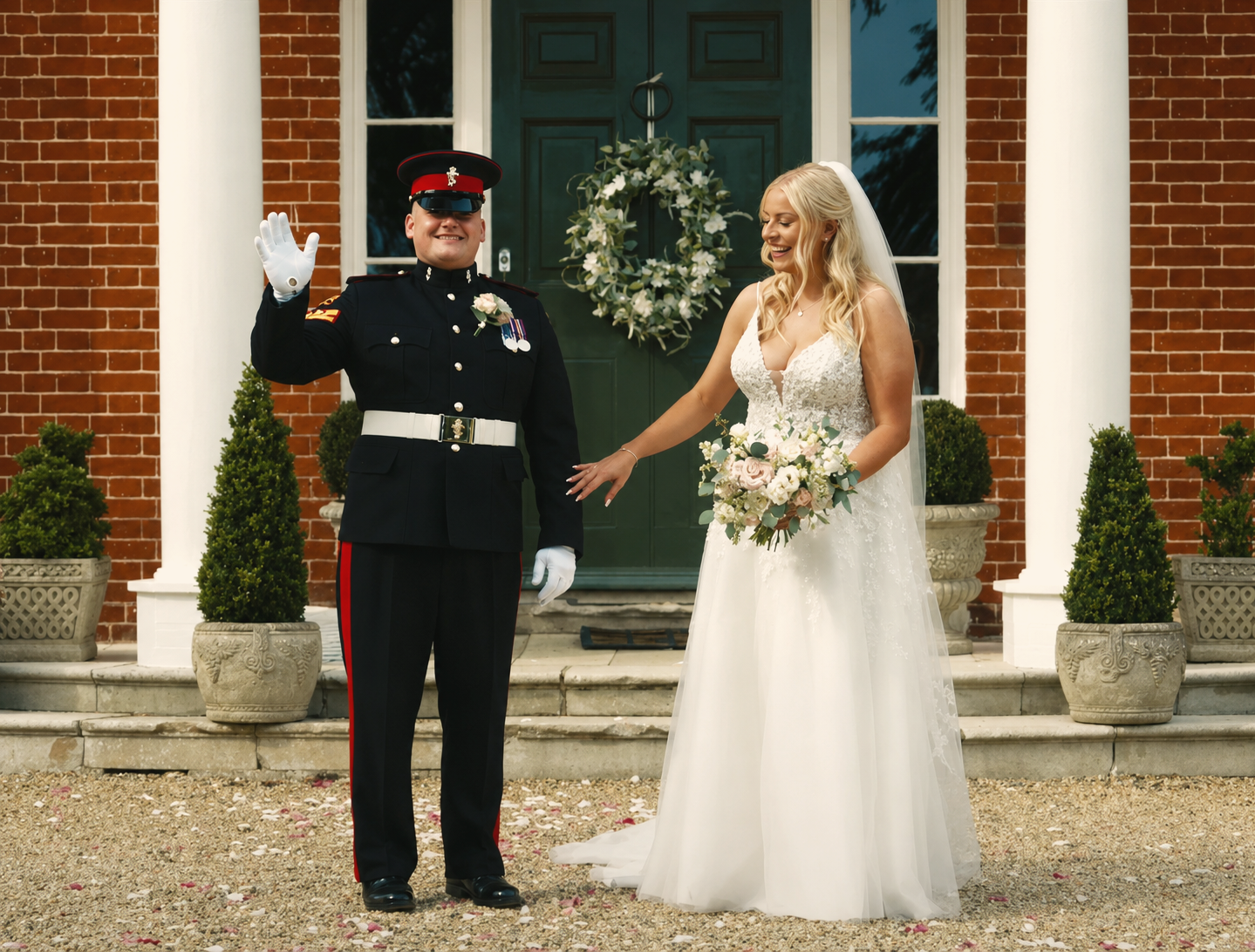 Military groom and bride celebrating outside Reymerston Hall after their wedding ceremony, featured in a documentary-style wedding film.