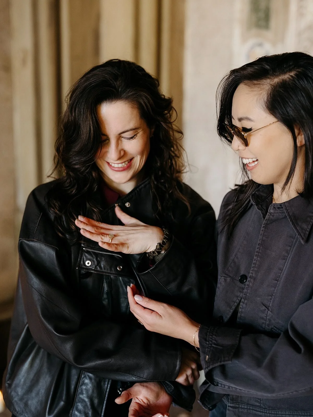 Two women looking at something on a smartphone, smiling and appearing happy.