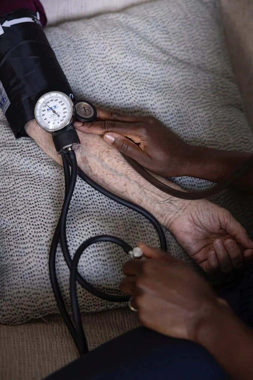 A healthcare worker measures a patient's blood pressure using an automatic cuff and stethoscope.