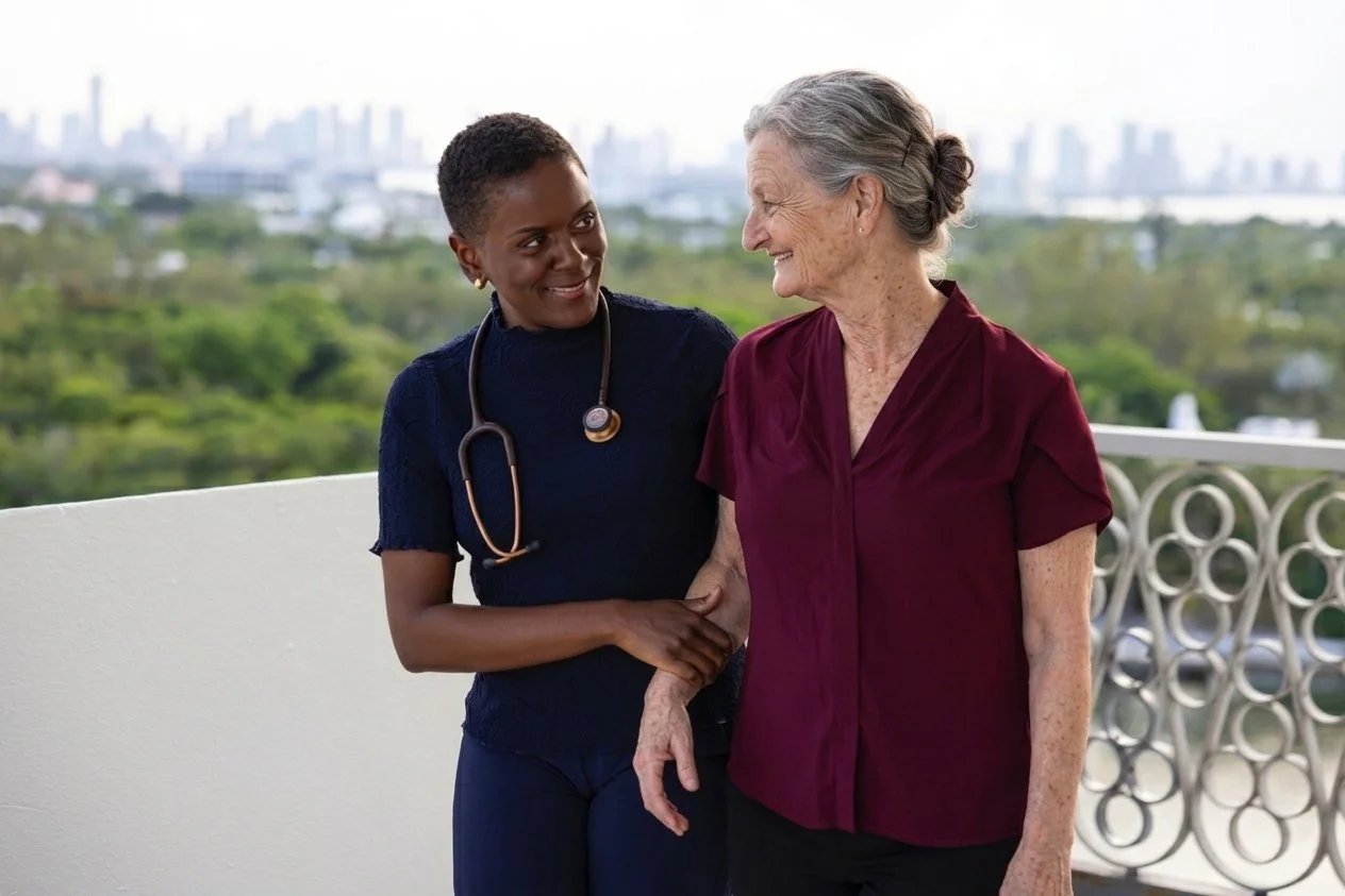 A healthcare professional and an elderly woman sharing a moment on a balcony with cityscape in the background.