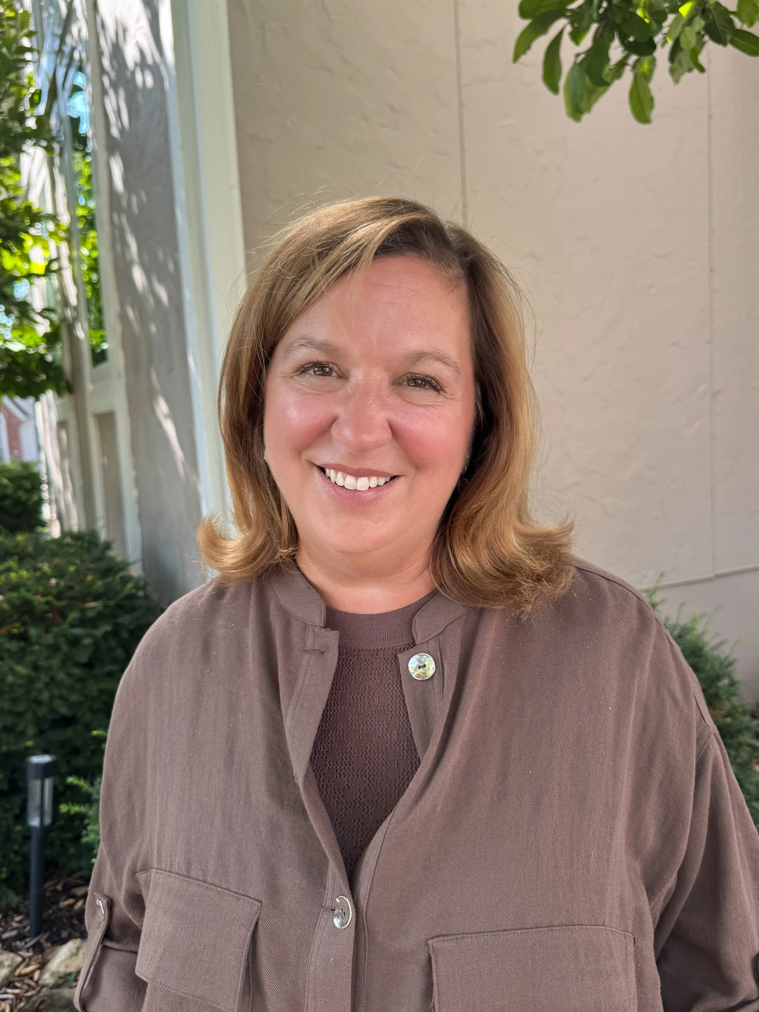 Clergy member smiling outdoors, wearing glasses and a clerical collar
