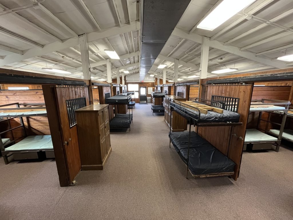 Dormitory room with multiple bunk beds and wooden partitions