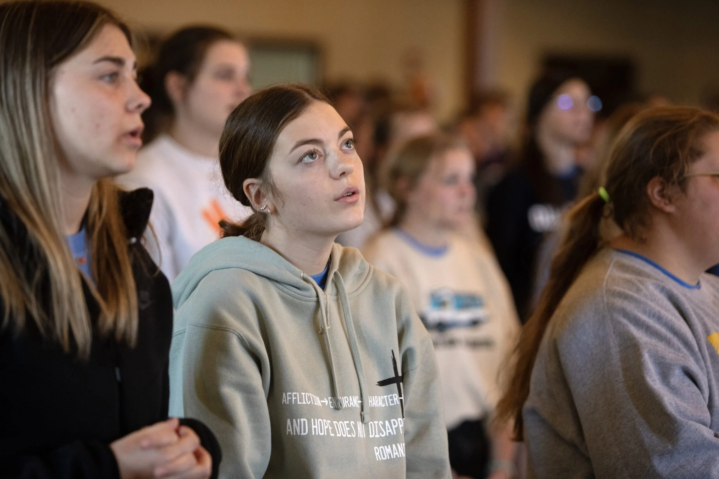 A group of young women attending a conference or seminar, focused on listening to a speaker.