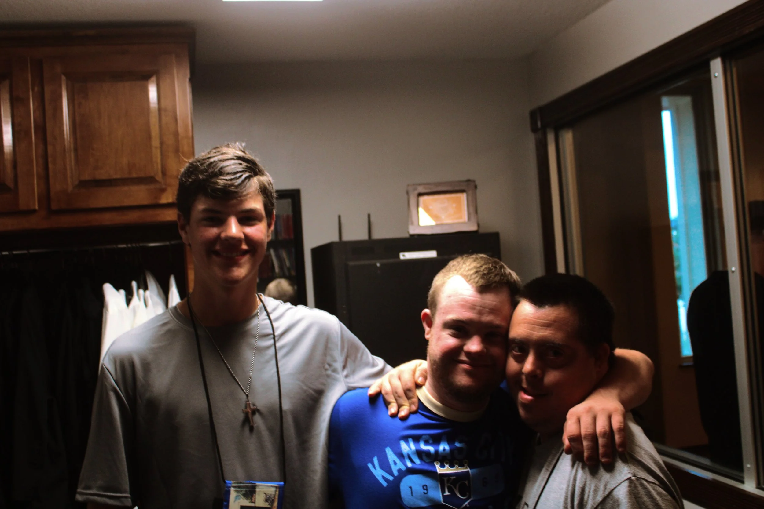 Group of young men smiling and posing together indoors, with one person wearing a Kansas City Royals shirt.