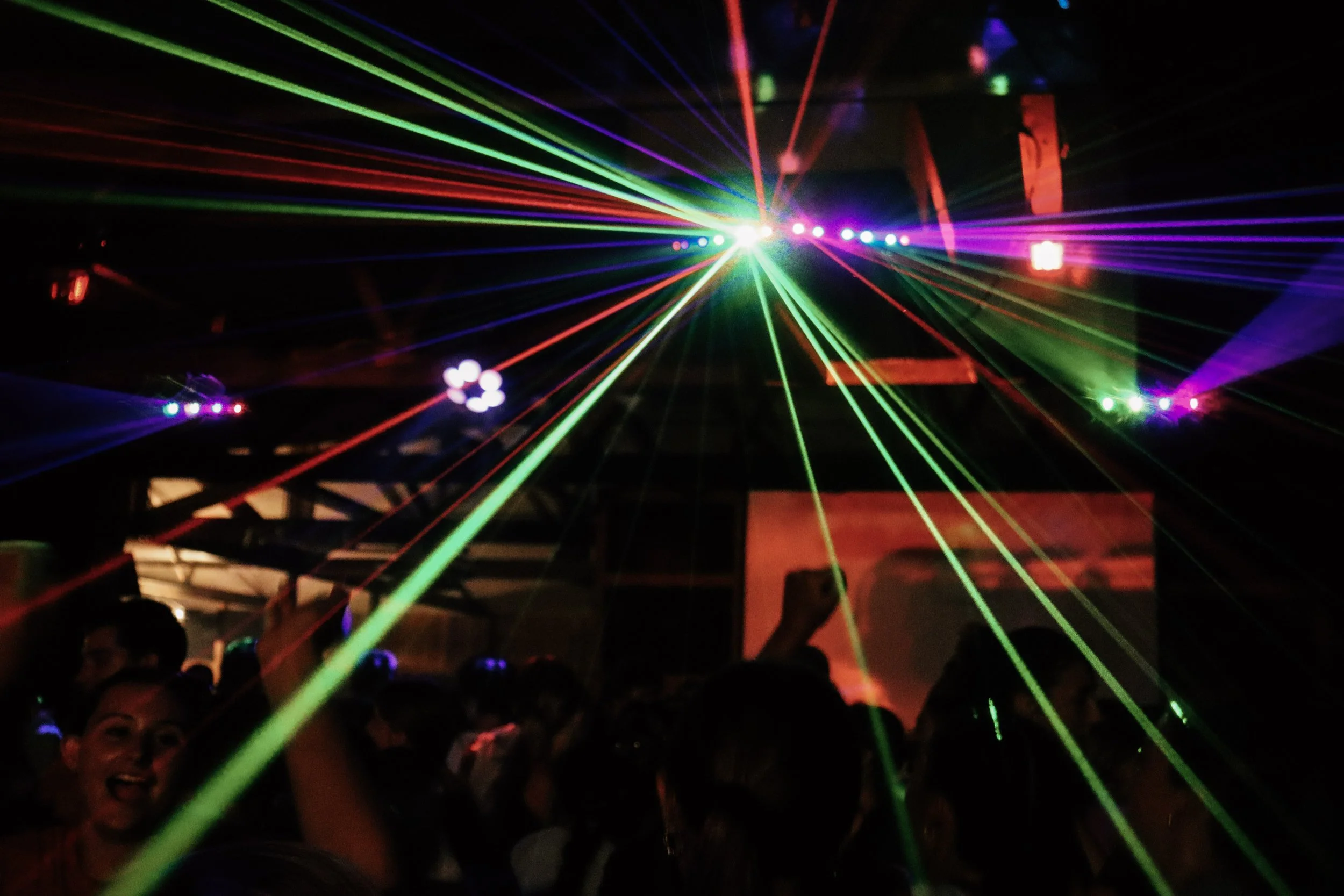 People enjoying a party with colorful laser lights illuminating the dark room.
