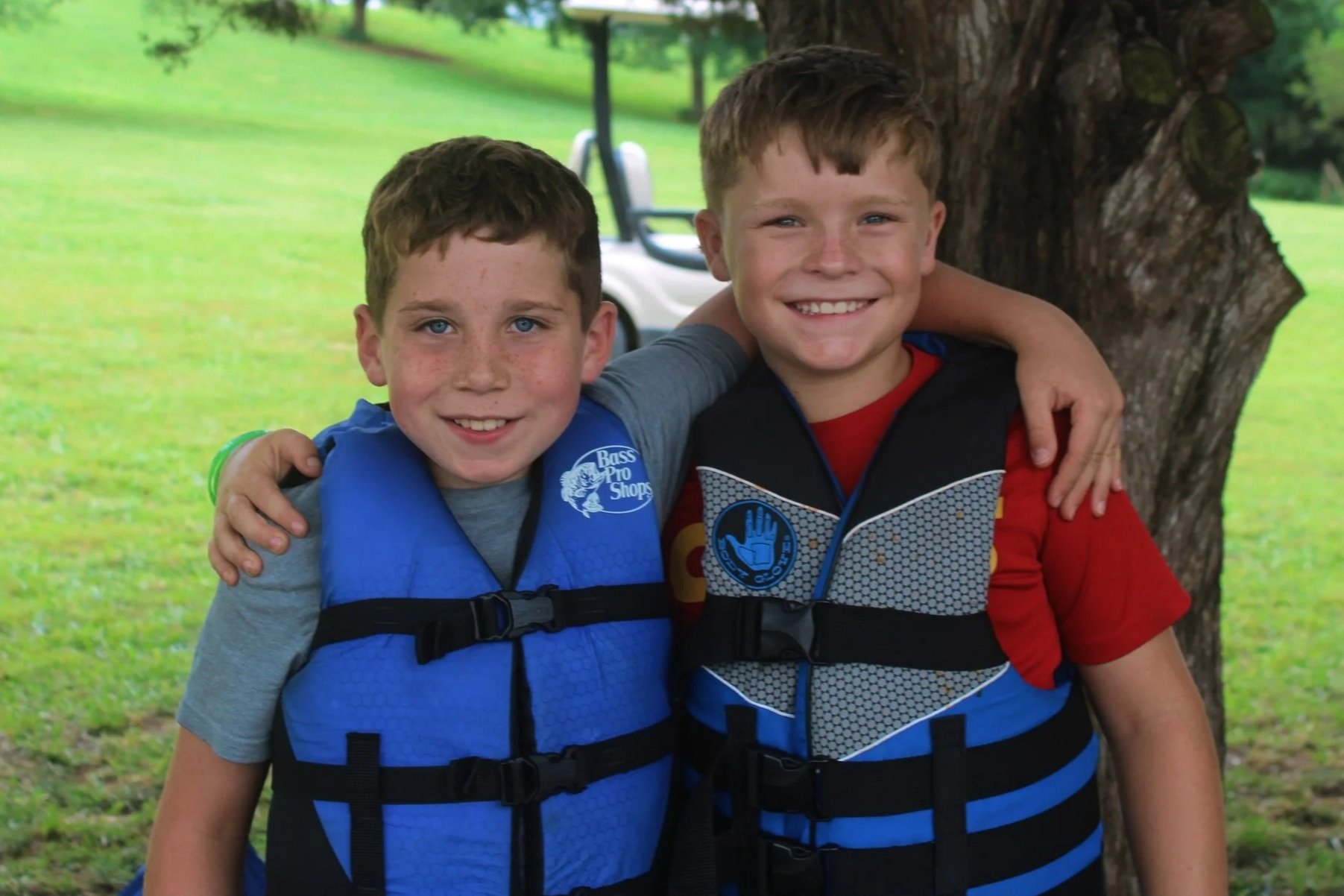 Two young boys smiling and wearing life jackets.