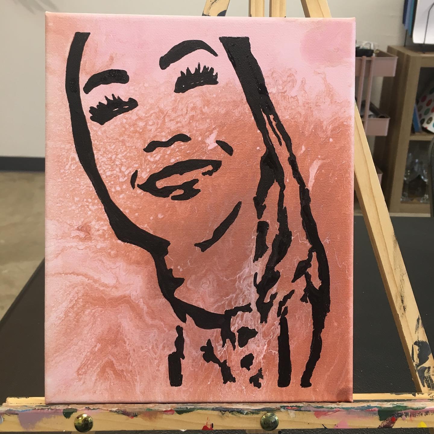 Abstract portrait of a woman with dark hair, closed eyes, smiling, painted on a pink textured background.