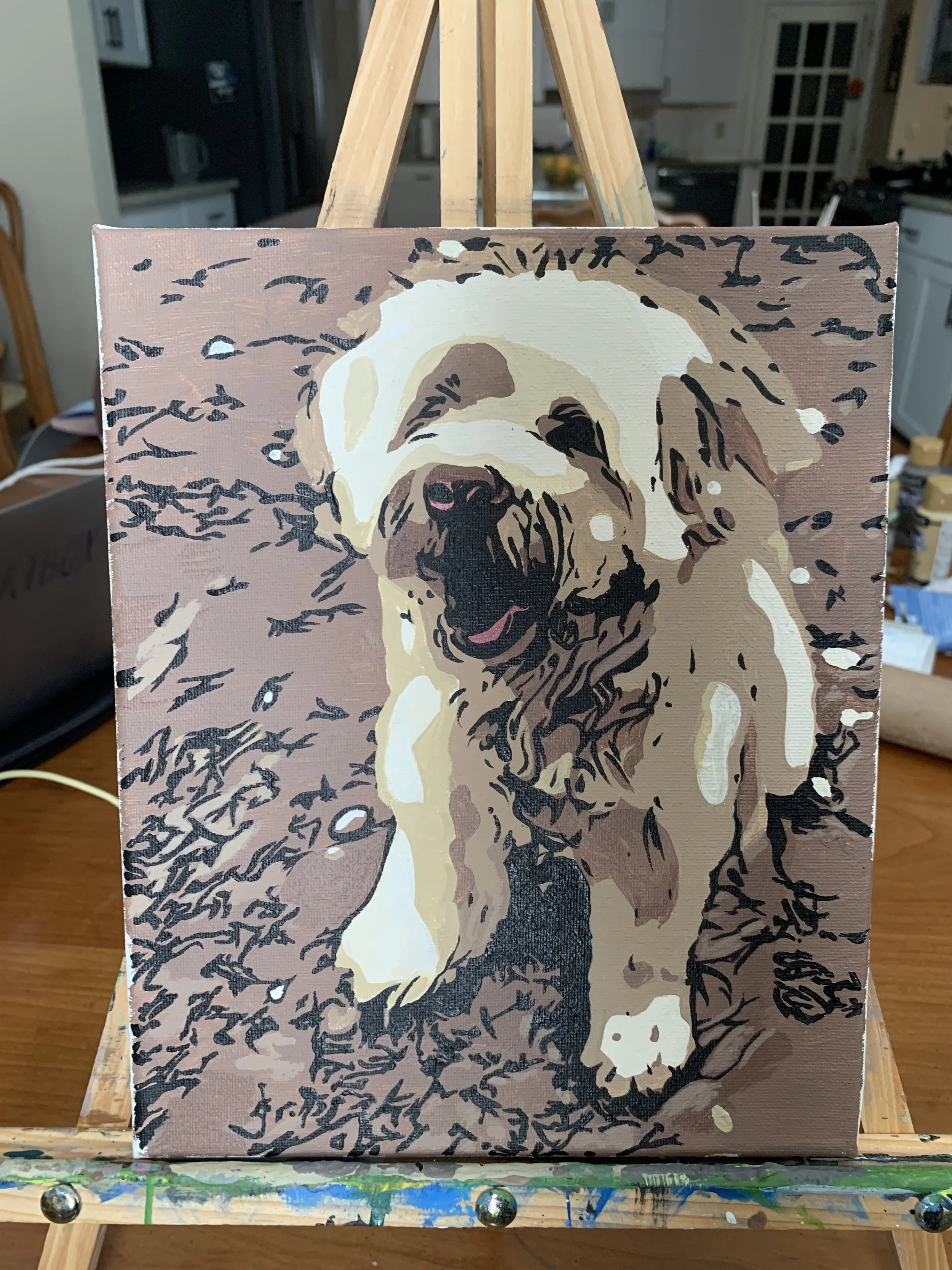 Painting of a Labrador Retriever dog with a cheerful expression, painted in a stylized, abstract manner on a canvas, set on an easel in a home kitchen.