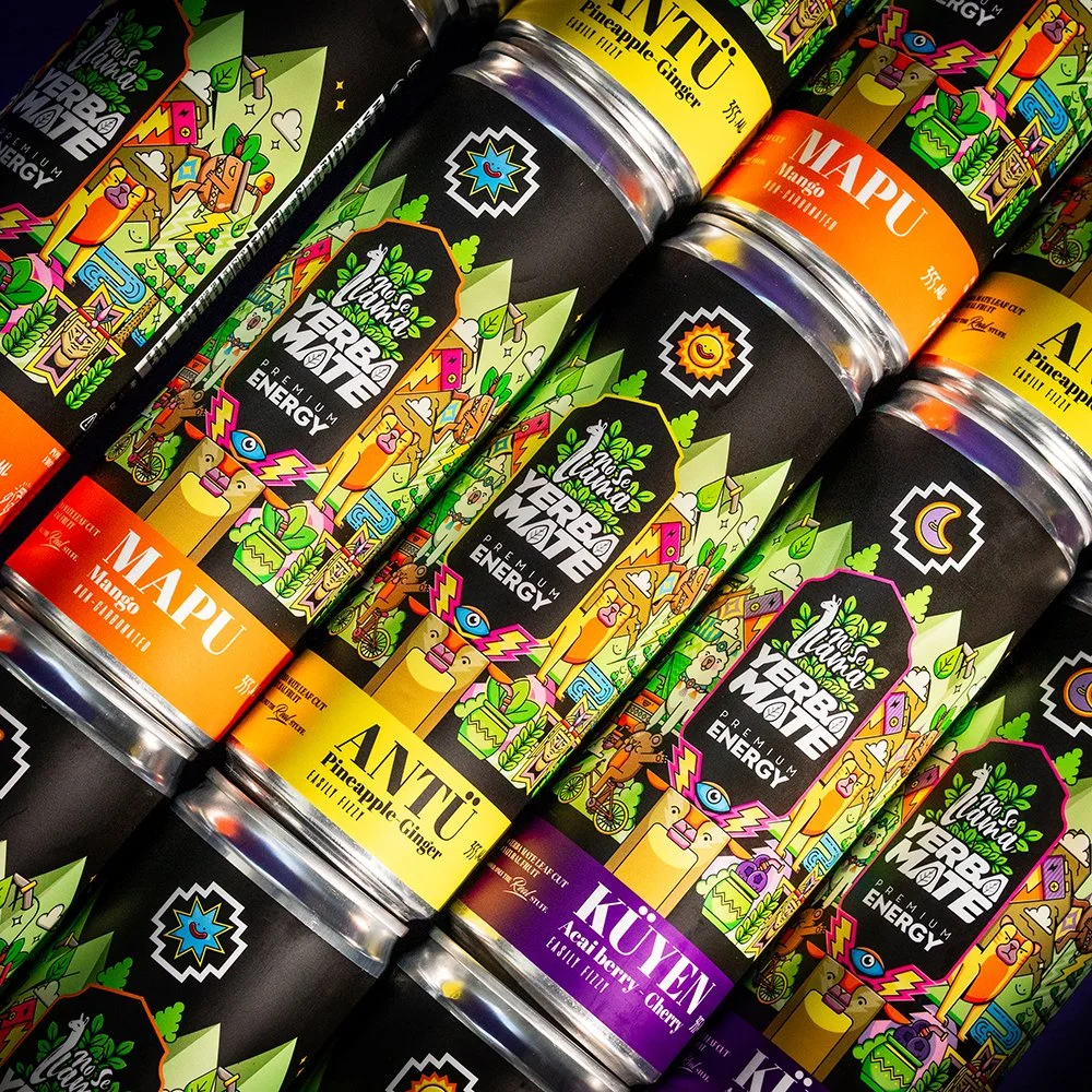 Multiple cans of colorful herbal mate energy drinks with lemon ginger, mango, and acai berry cherry flavors displayed upright.