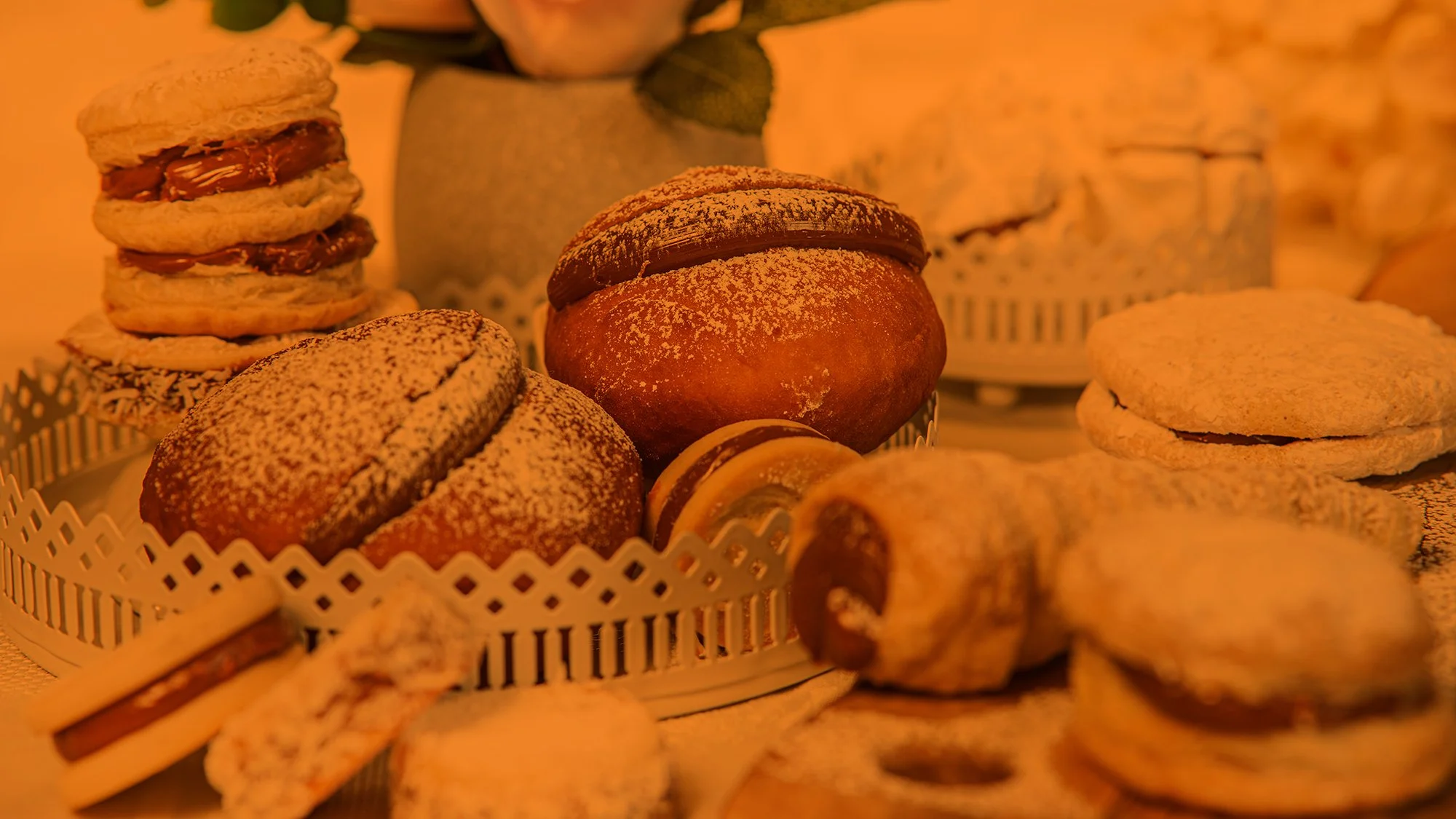 Various cookies displayed in a basket, including chocolate-filled shortbread, powdered sugar-dusted cookies, and rolled wafer cookies on a decorative tray.