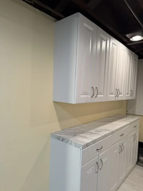 White kitchen cabinets with marble countertop in a room with beige walls.