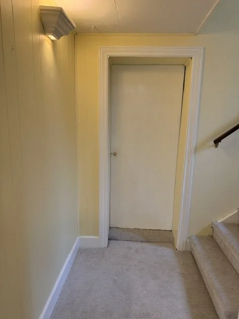 Empty closet door at the top of a staircase landing in a yellow-walled room.