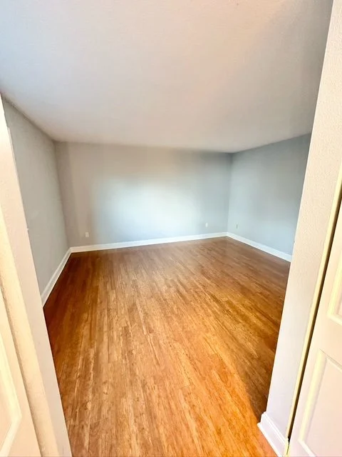 Empty room with wood flooring and light gray walls seen from doorway