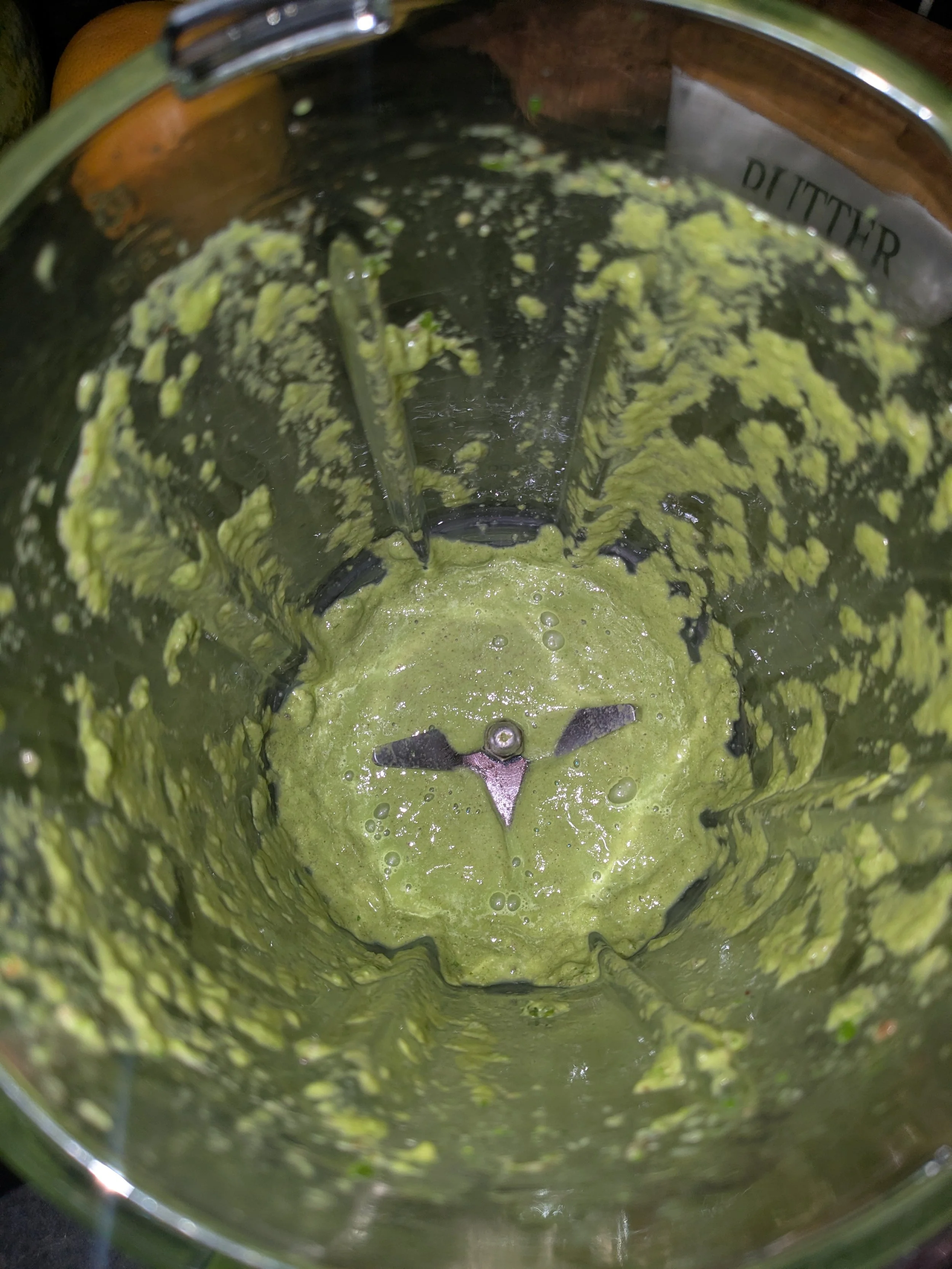 Blended green substance inside a blender, likely made from leafy greens.