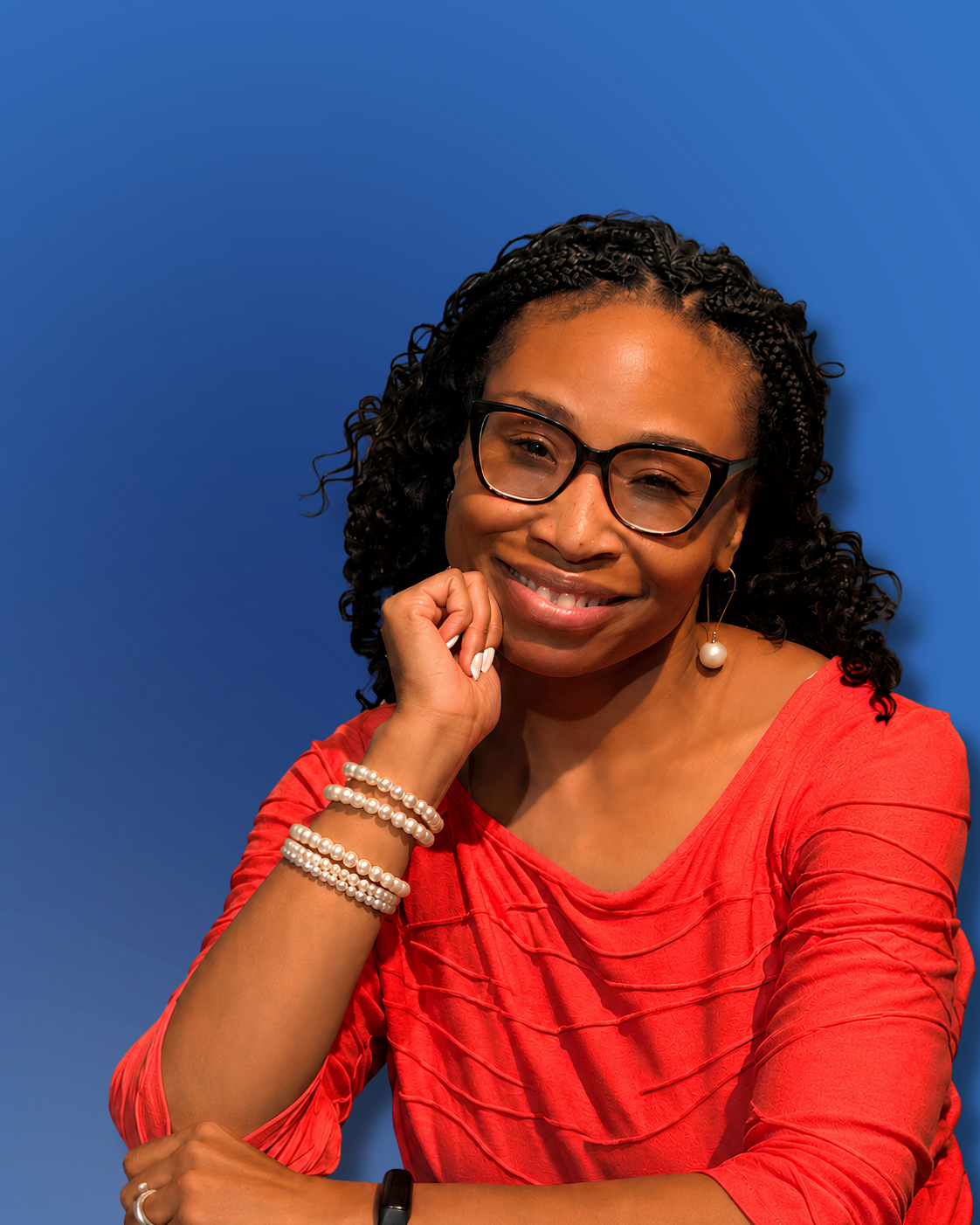 A woman with curly black hair, glasses, and pearl jewelry, smiling and resting her chin on her hand, against a blue background.