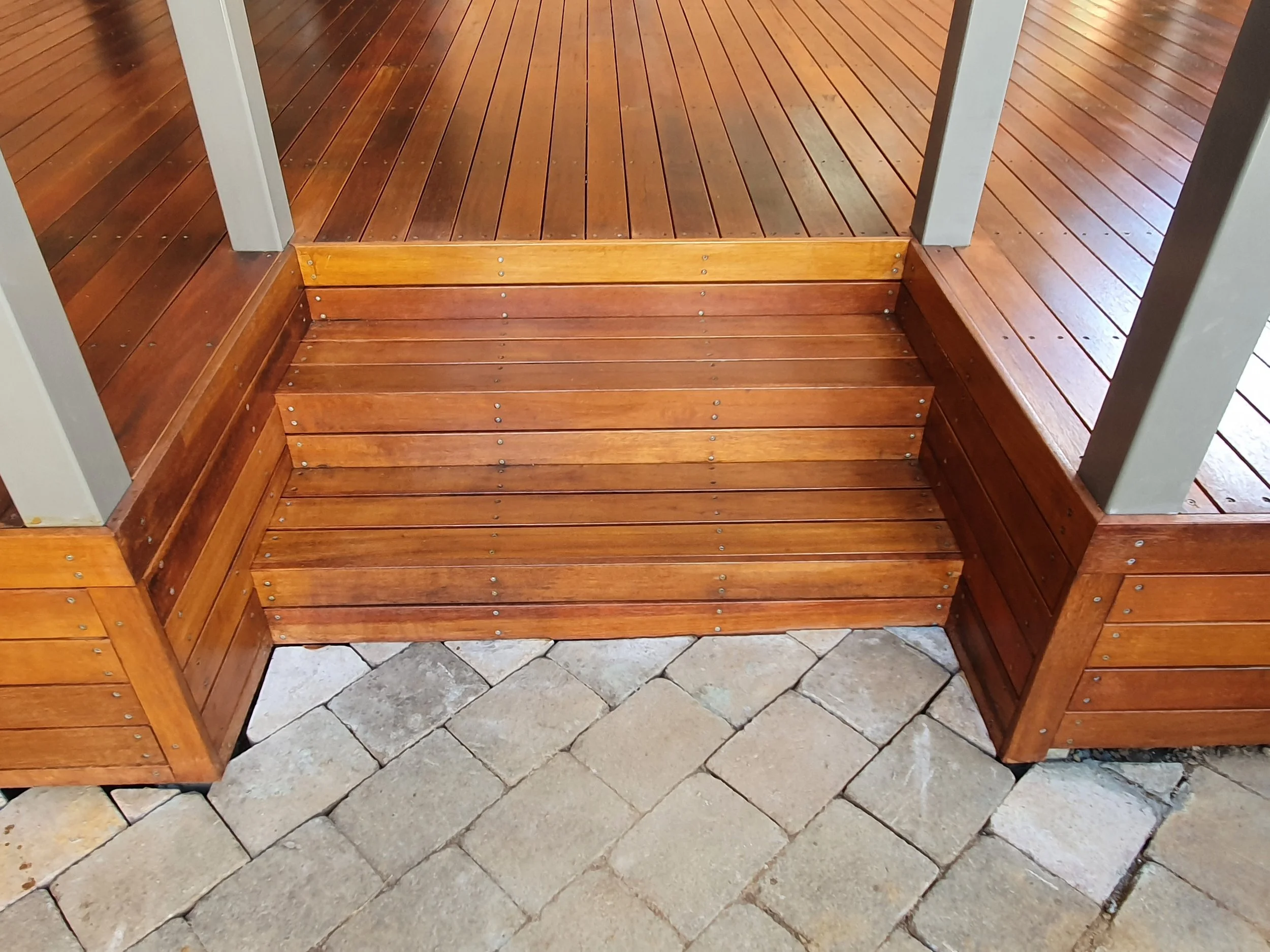 Wooden steps and a wooden deck transition onto a tiled stone floor.