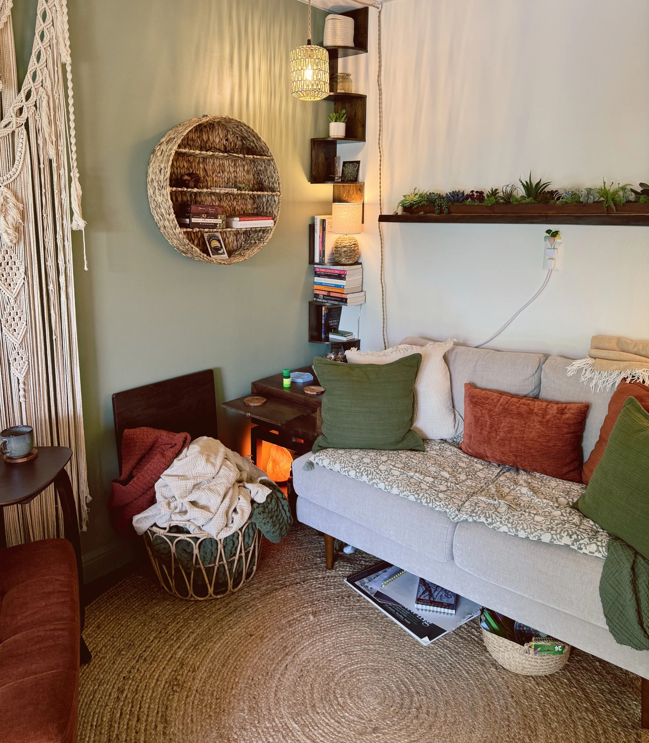 cozy sitting area with a couch, pillows, blankets, decor and shelves, books, and fidgets