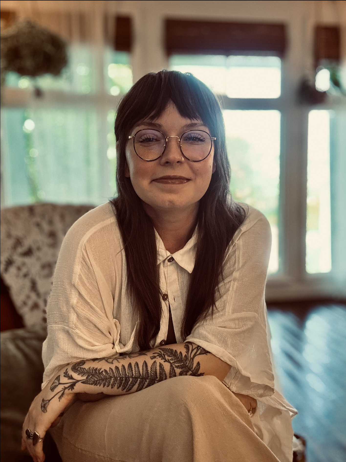 a smiling therapist who is sitting in a chair in a light-filled office