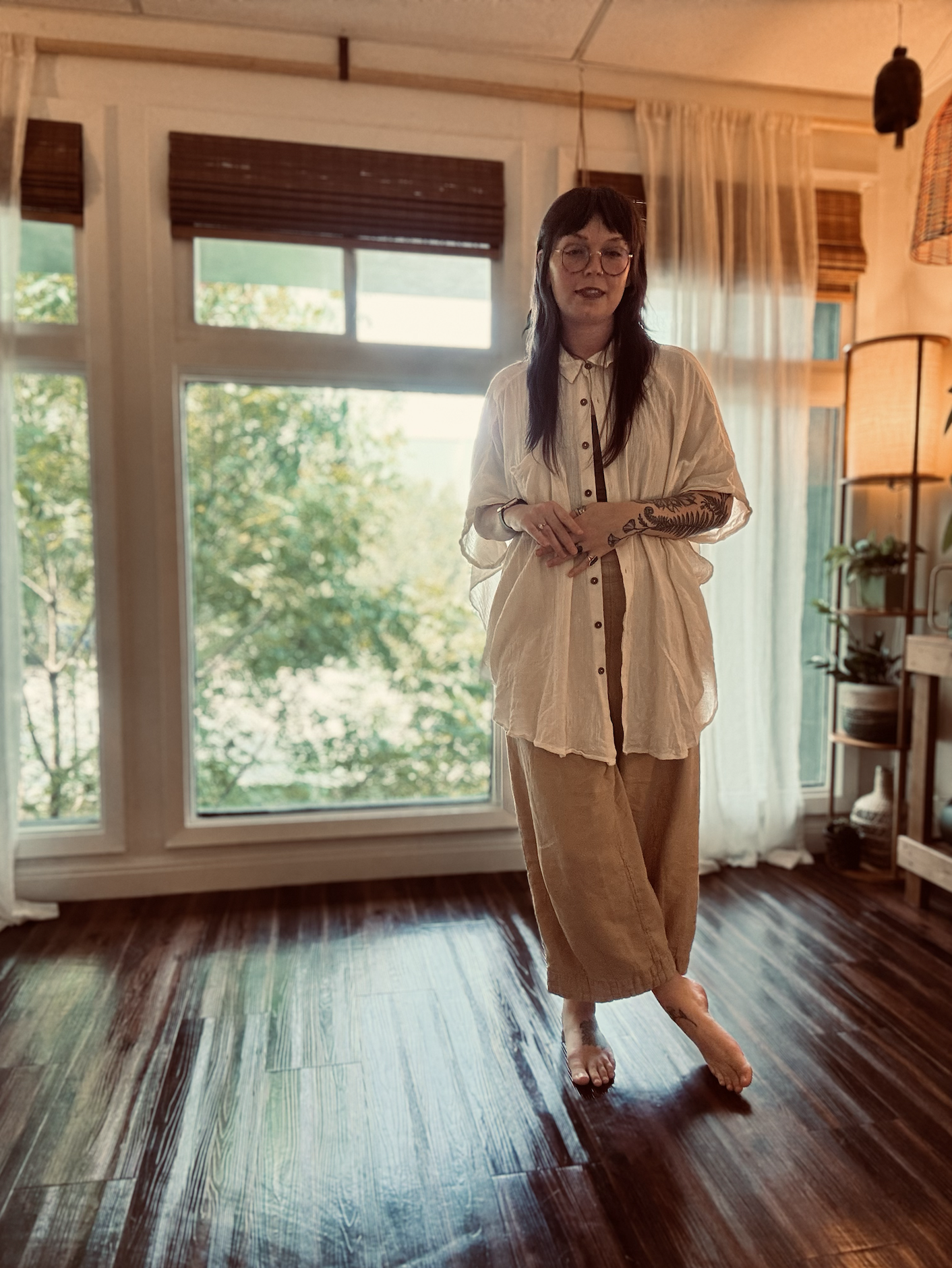 a therapist standing in a light-filled office space near windows and plants