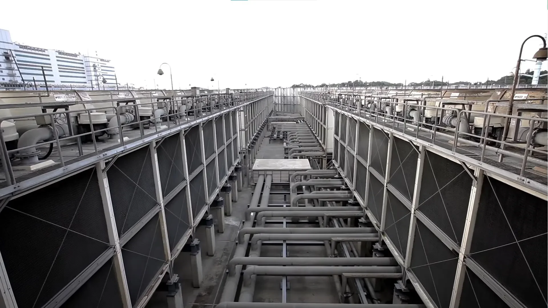 Vista de una planta de aire acondicionado con varias unidades y tuberías de metal en un techo urbano.